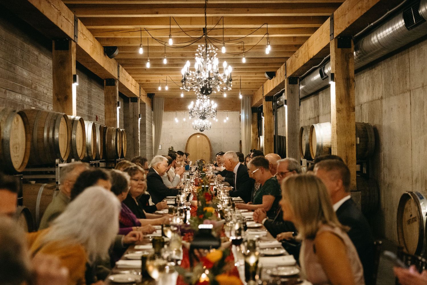 Elegant wine cellar reception setup with long tables and hanging chandeliers.
