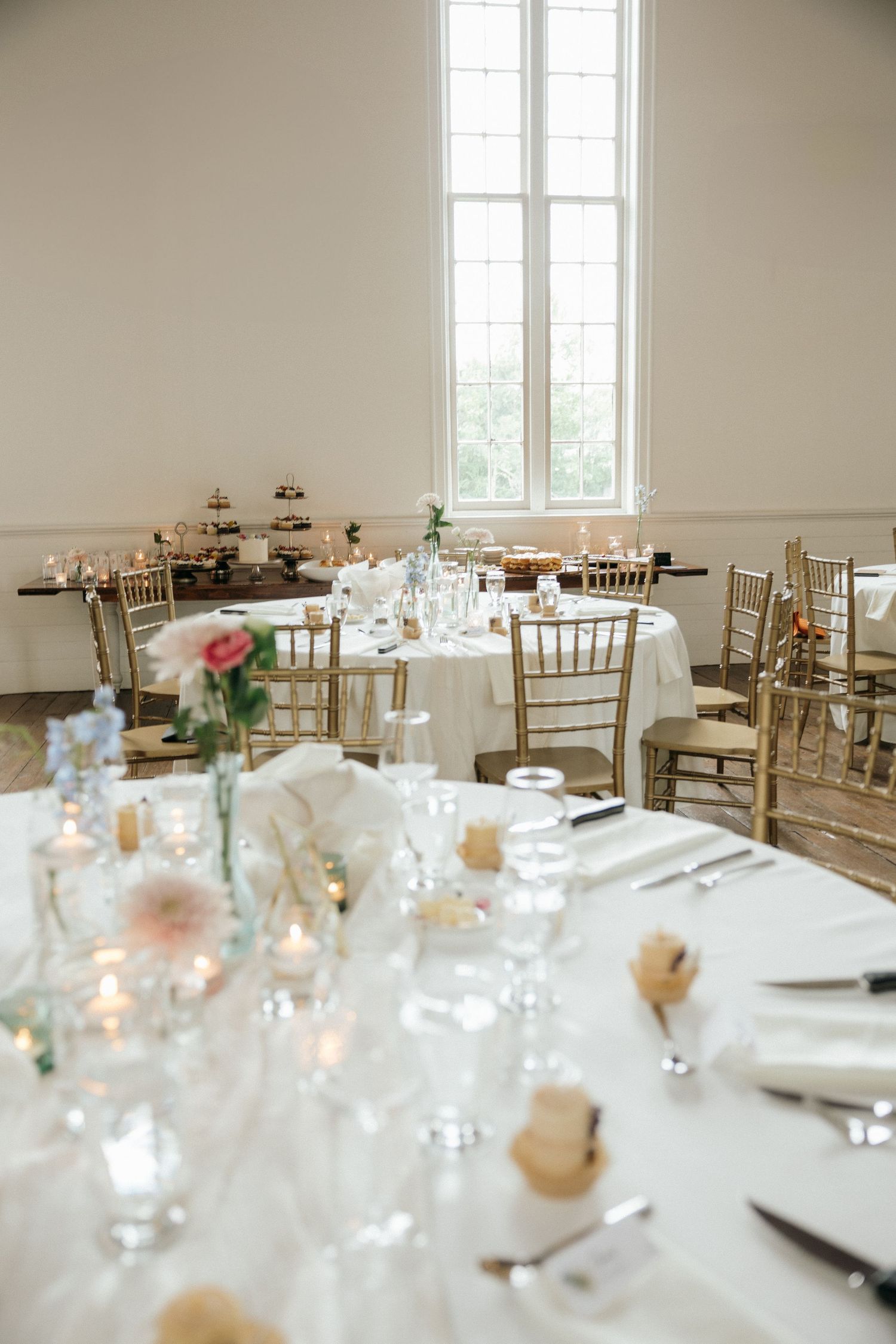 Bright, airy wedding reception venue with white tablecloths and wooden chiavari chairs.