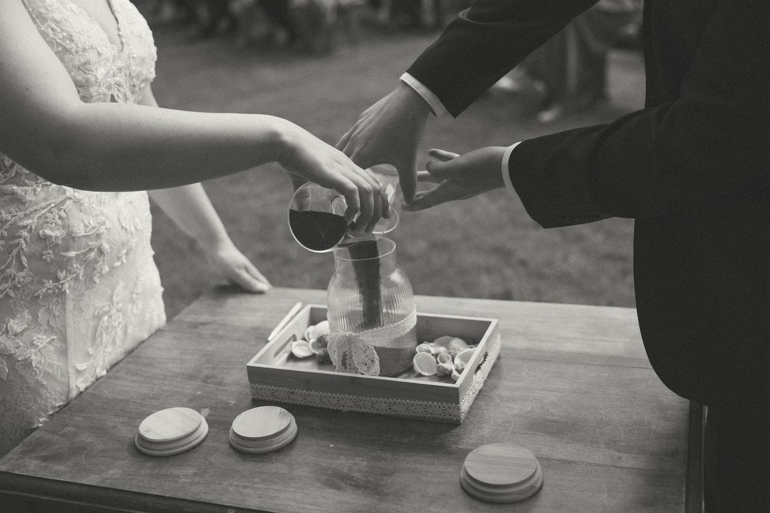 Close-up of hands exchanging rings during a wedding ceremony on a wooden surface.