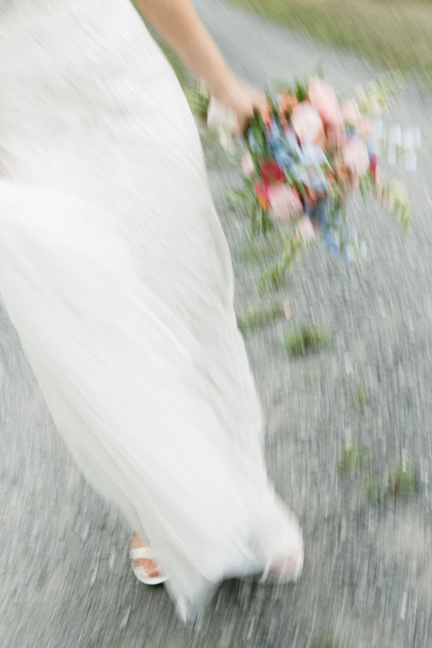 Motion blur of white wedding dress and flowers being thrown in celebration.