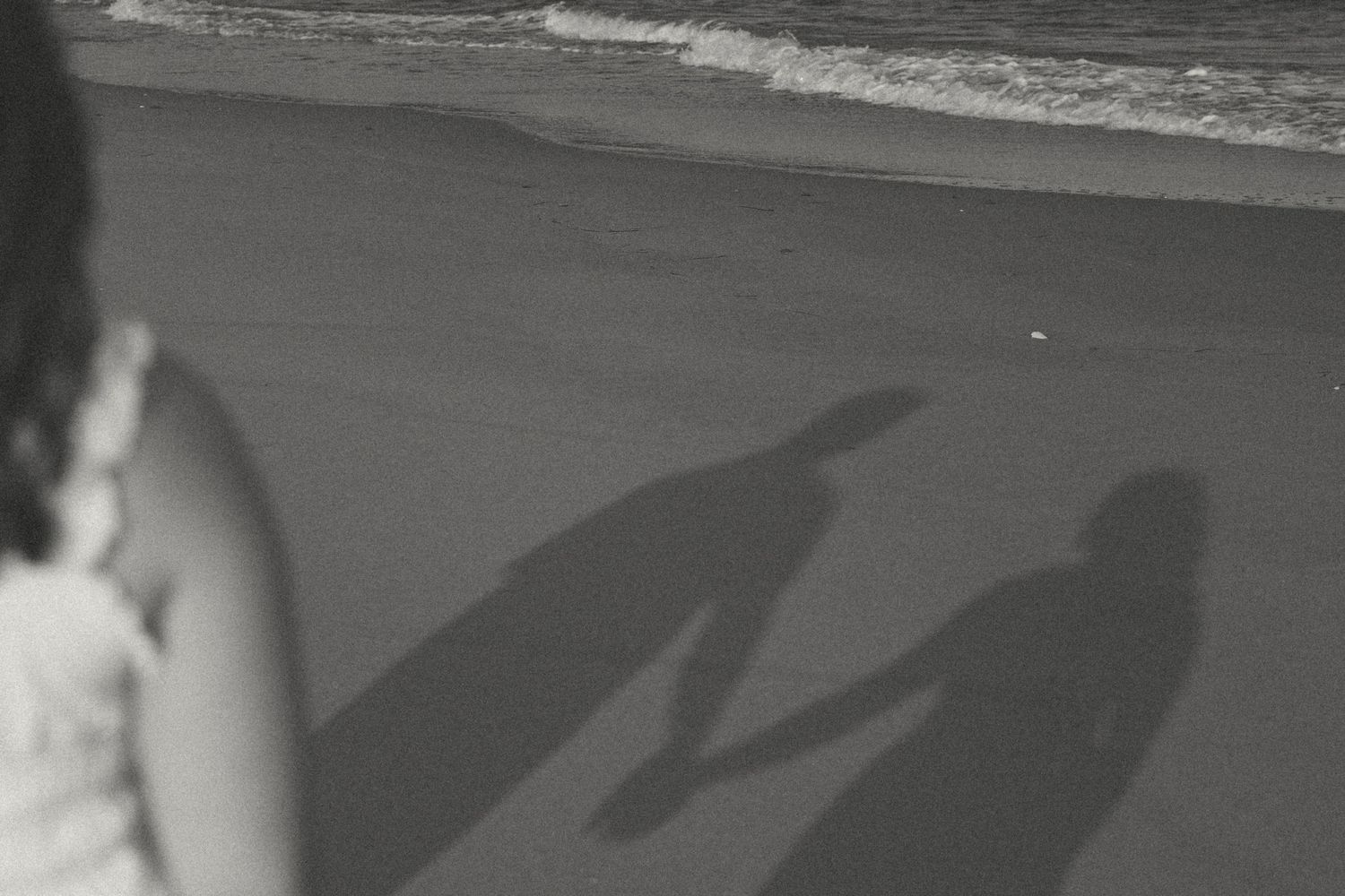 Long shadows cast on a sandy beach during sunset.