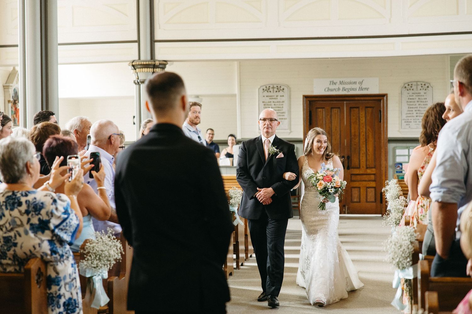 Wedding ceremony processional in a bright church interior.