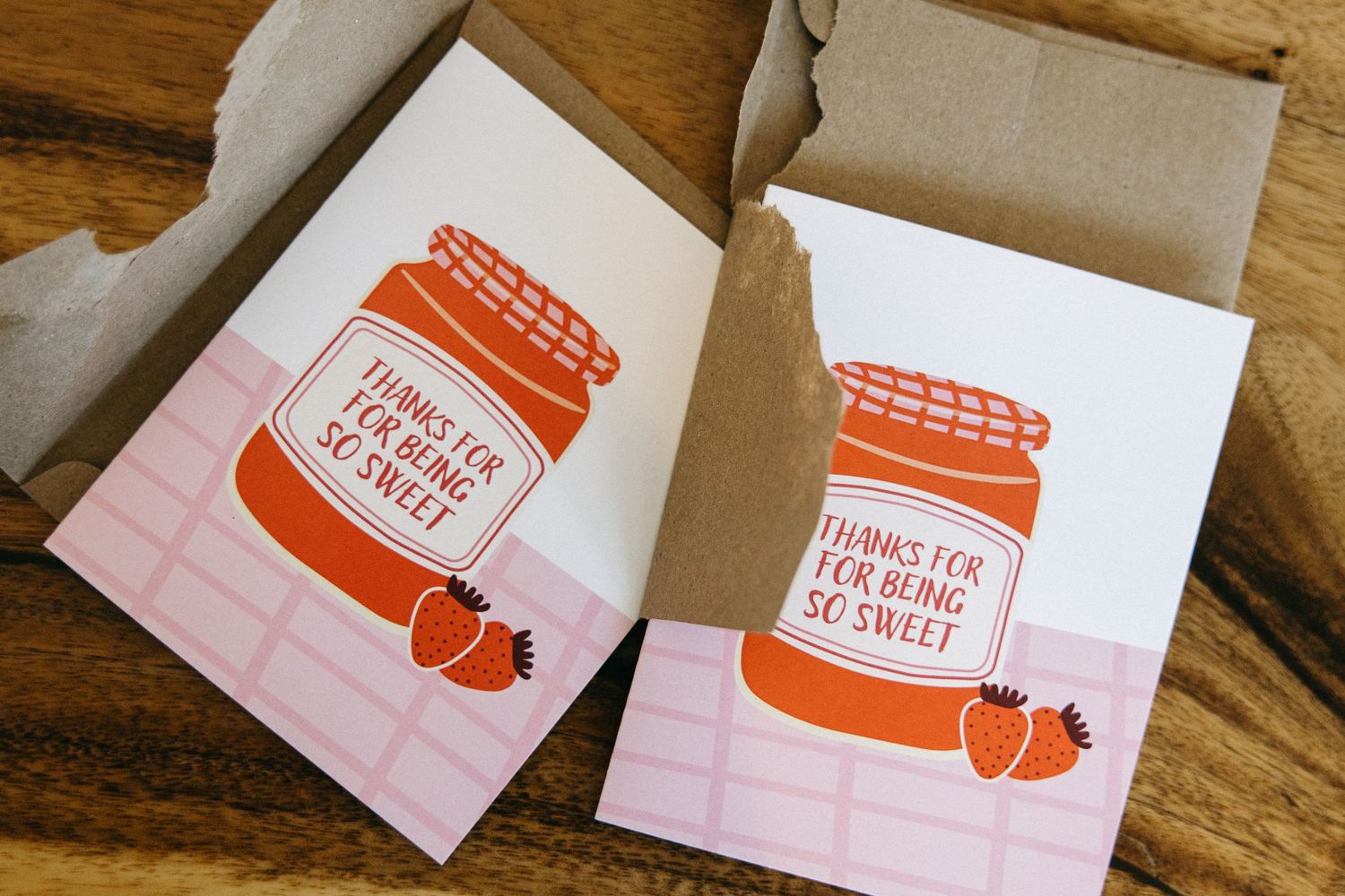 Orange and pink printed thank you cards arranged on wooden surface.