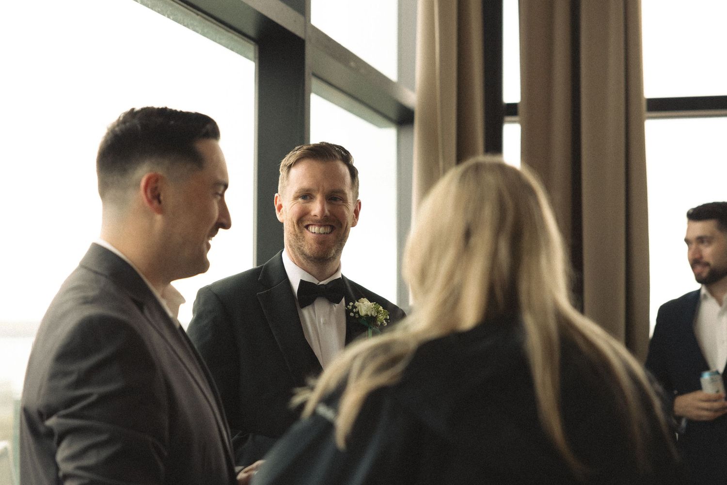 People socializing in an indoor venue with large windows and natural light.