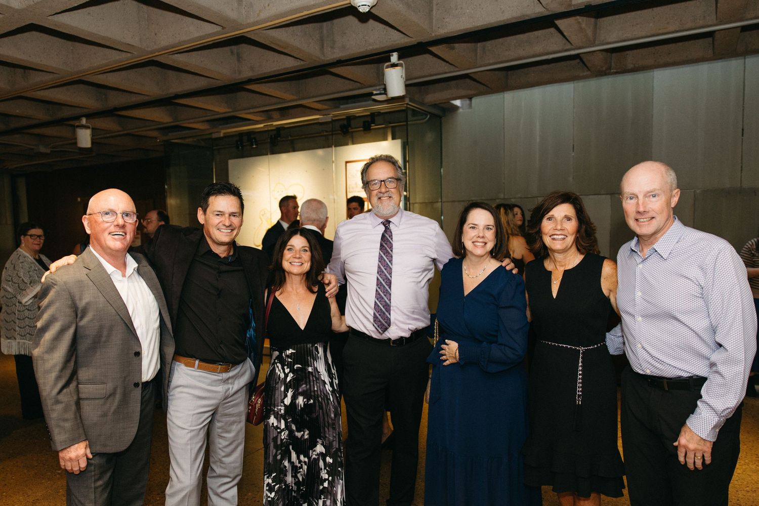 Group photo of formally dressed guests at an indoor celebration.