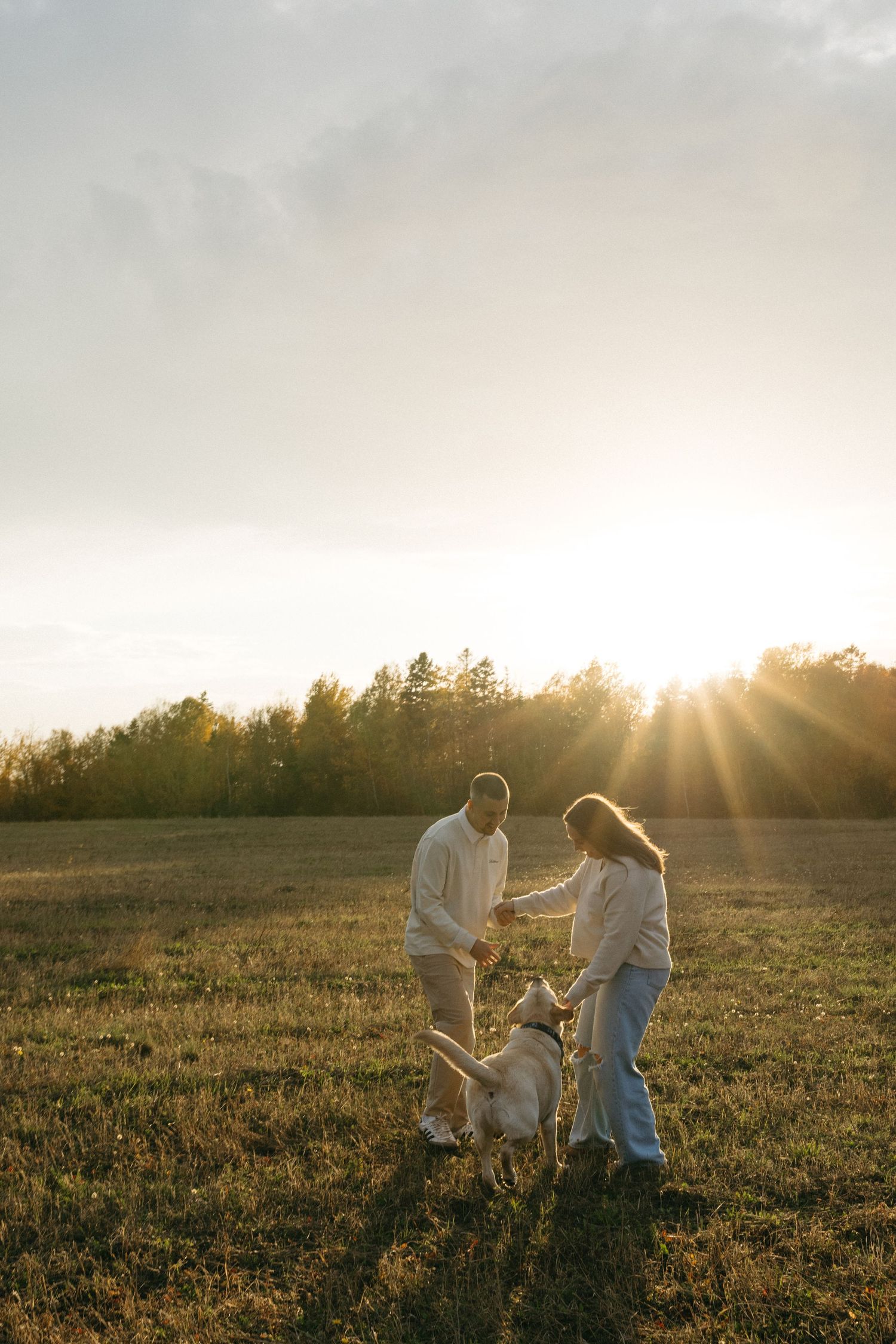 People enjoying a playful moment together in a sunlit autumn field.
