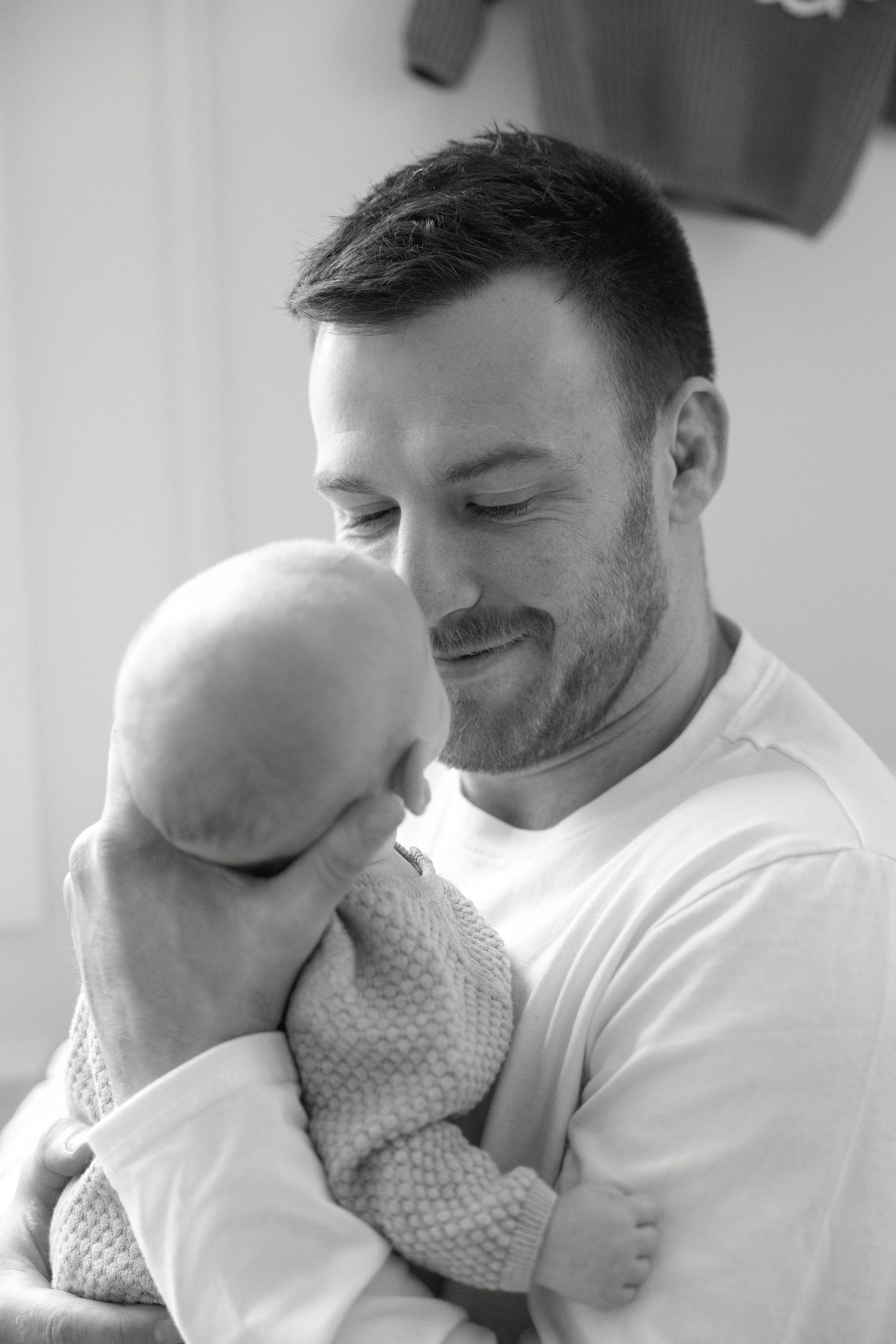 A heartwarming black and white portrait capturing an intimate moment in a bright nursery setting.