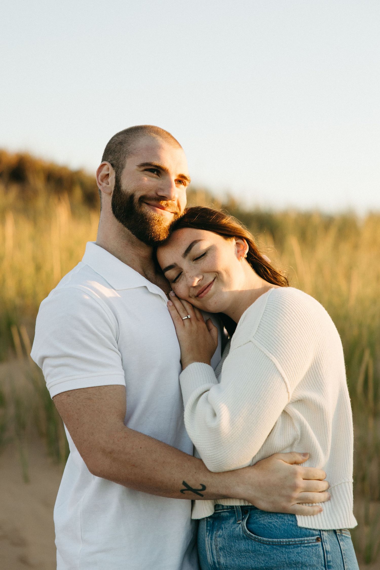 Couple embracing tenderly in a field during golden hour photography session.