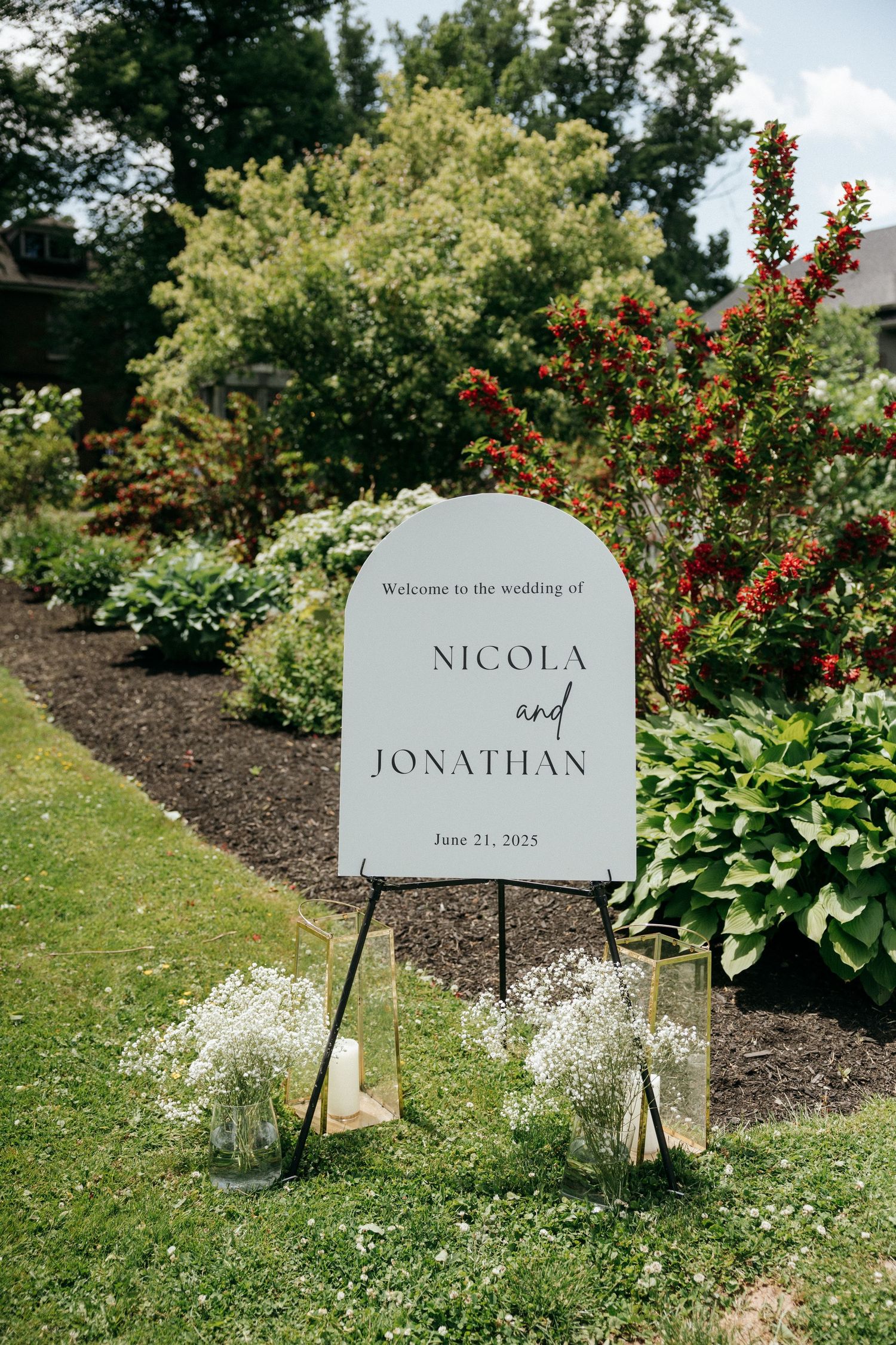 Elegant wedding welcome sign for Nicola and Jonathan displayed in a garden setting.