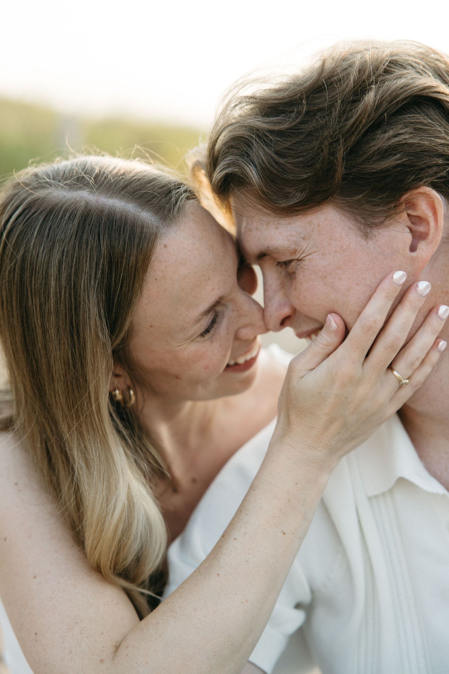Close-up of couple sharing tender moment, woman with white nails gently holding man's face near hers.