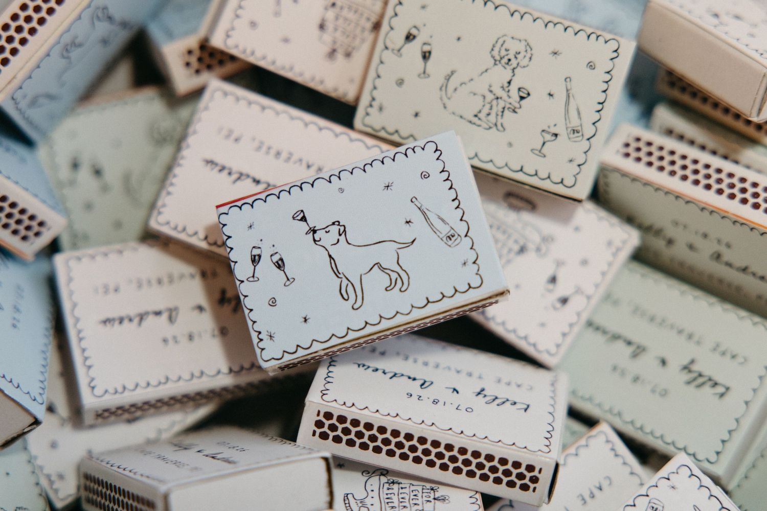 Decorative custom illustrated matchboxes with cat and dog drawings as wedding favor details.