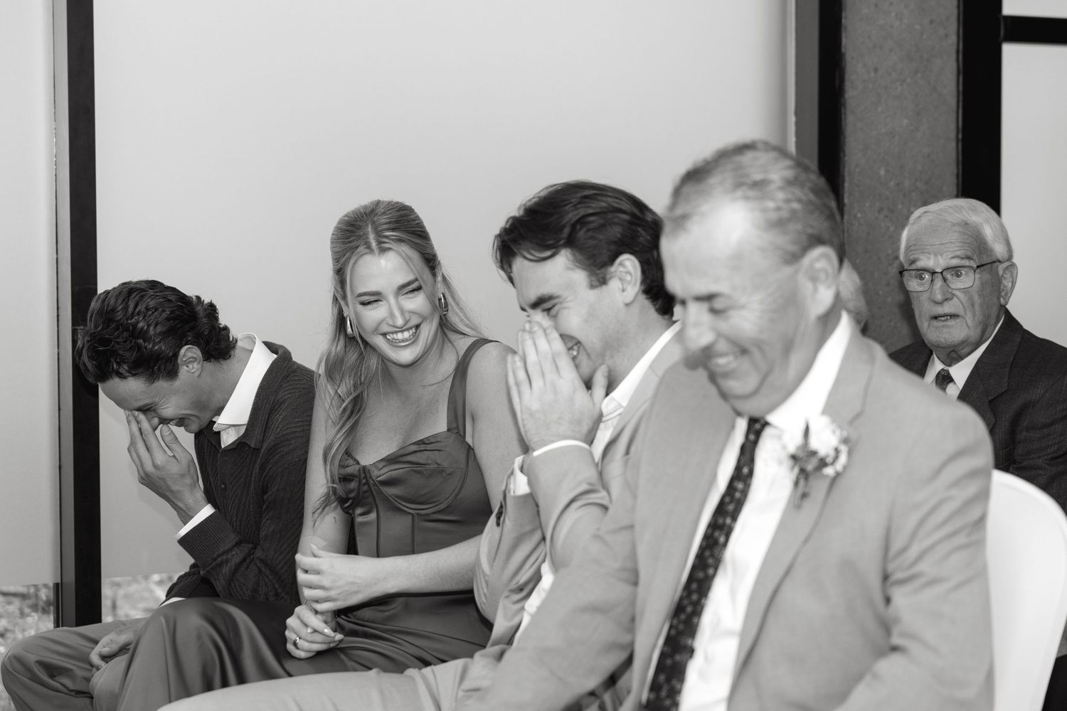 Group of people sharing a candid laughing moment at a formal event.