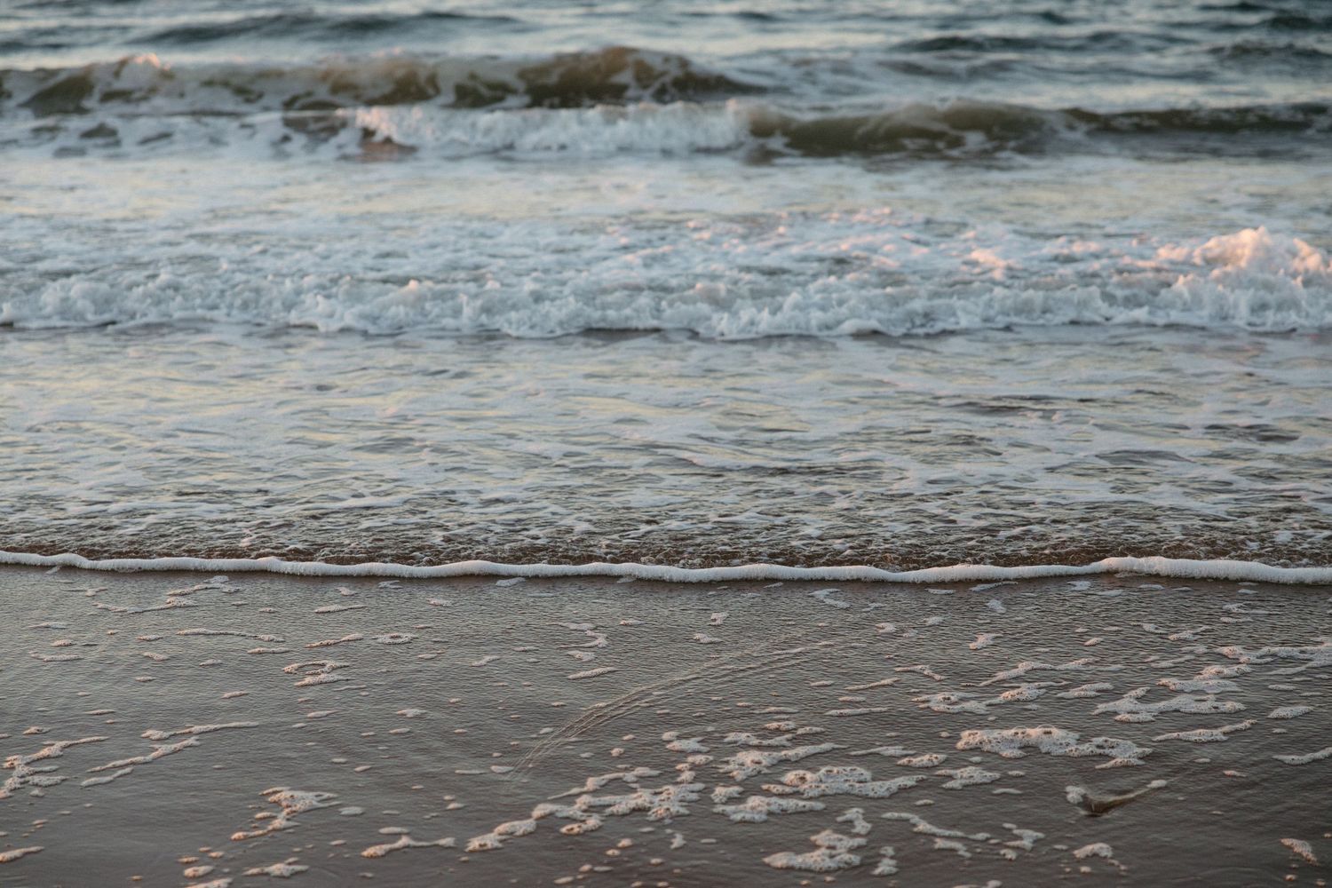 Ocean waves roll onto shore during sunset creating a serene coastal landscape.