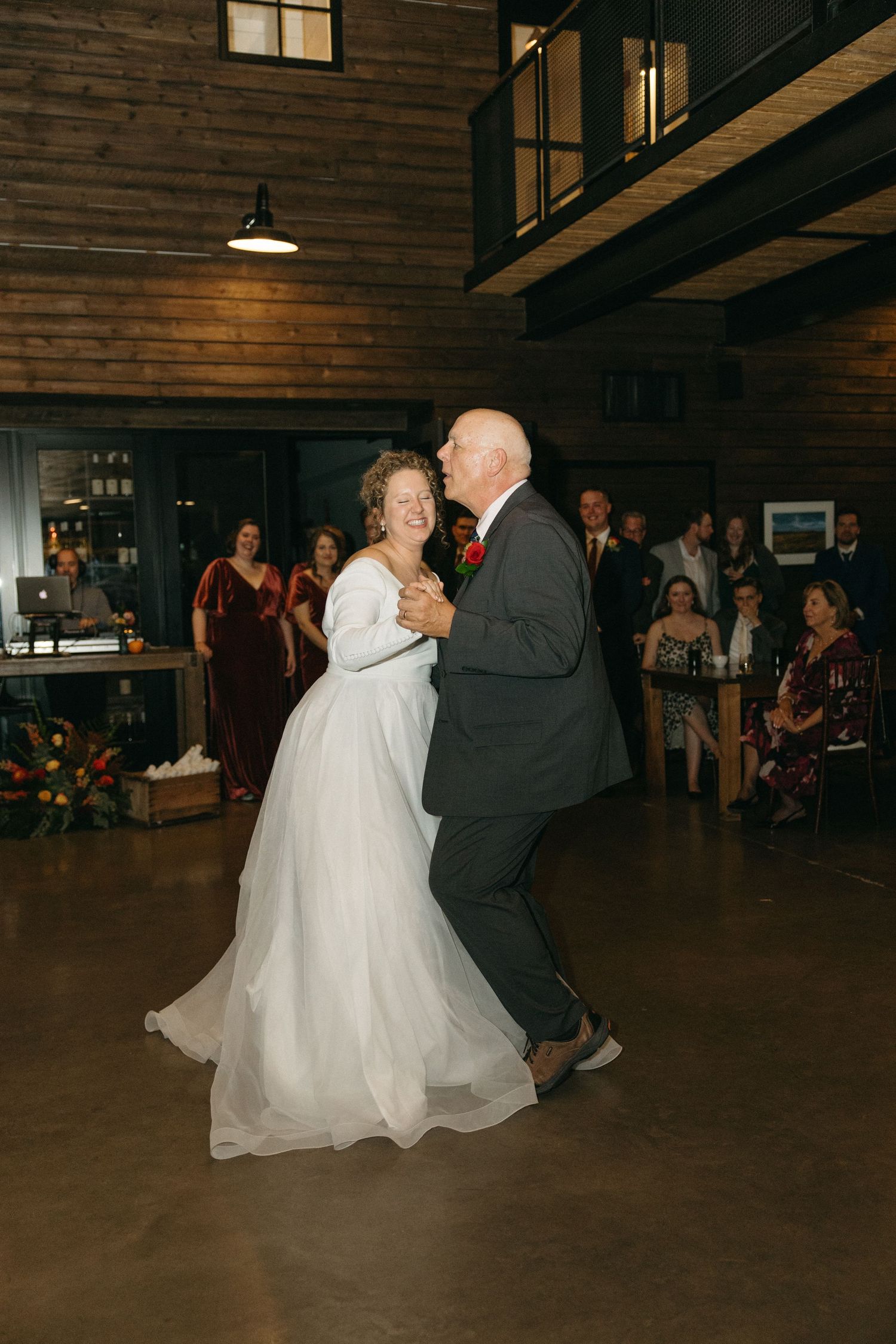Couple performing a romantic dance in a rustic wooden venue with guests watching.