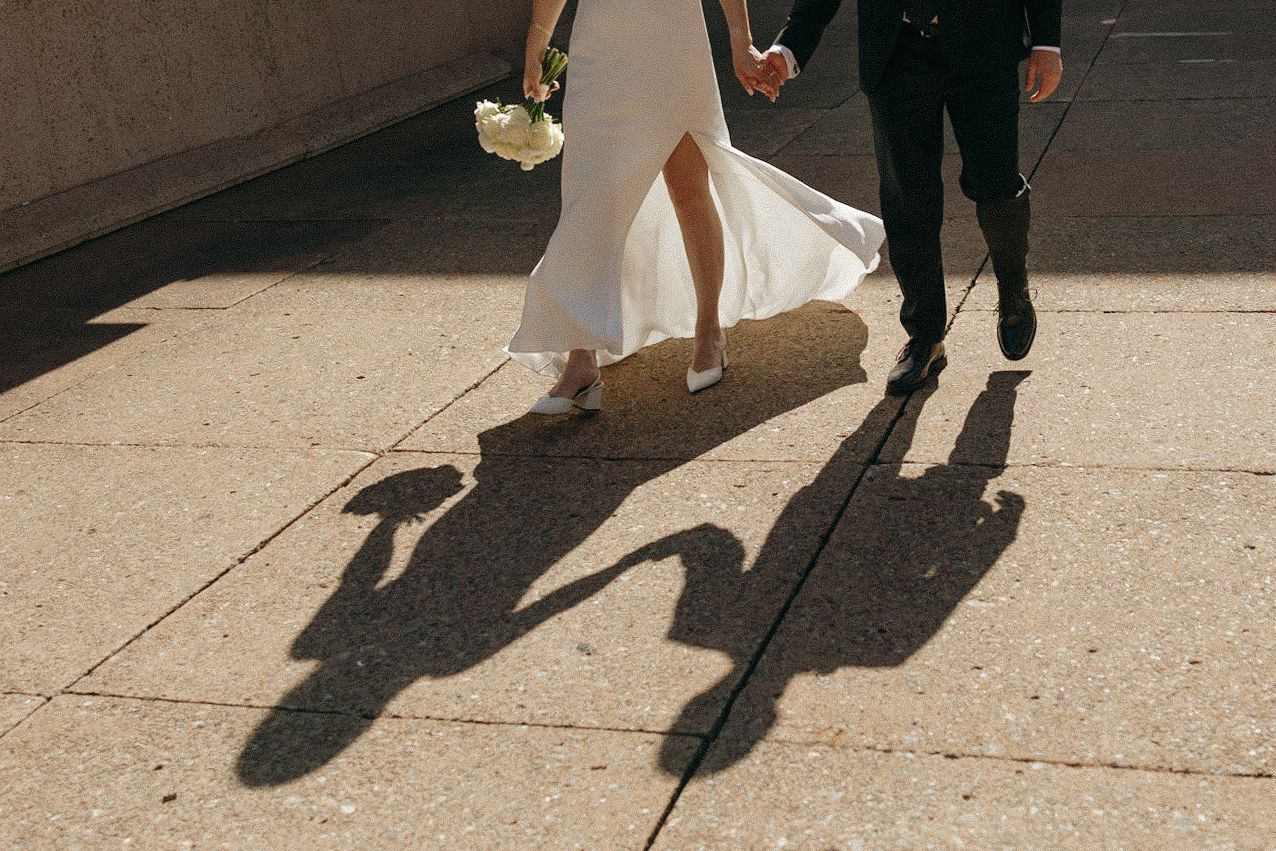 Wedding couple's shadows cast on concrete during a sunny day.