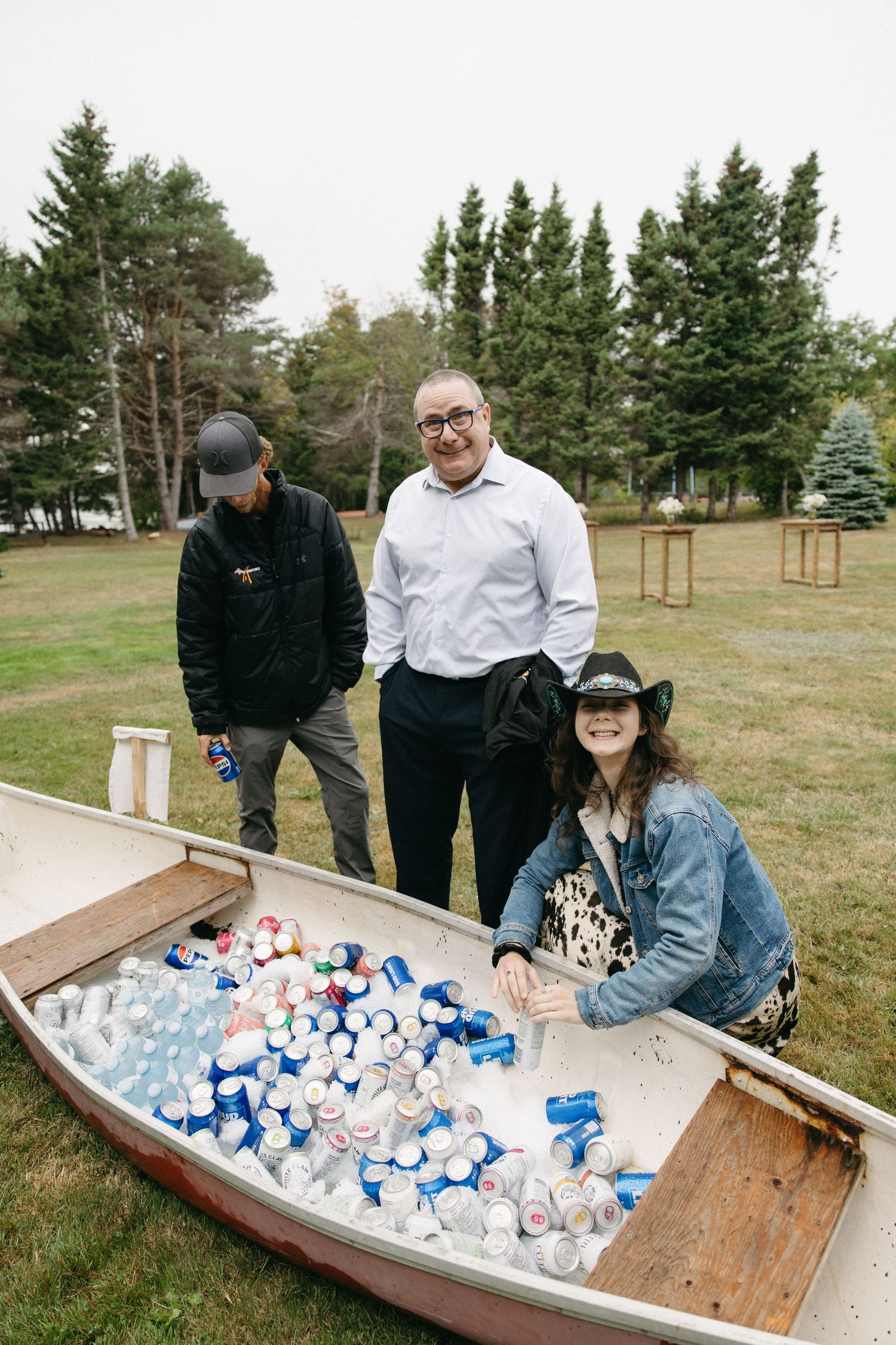 A wooden boat filled with ice and beverages serves as a rustic drink cooler at an outdoor event.