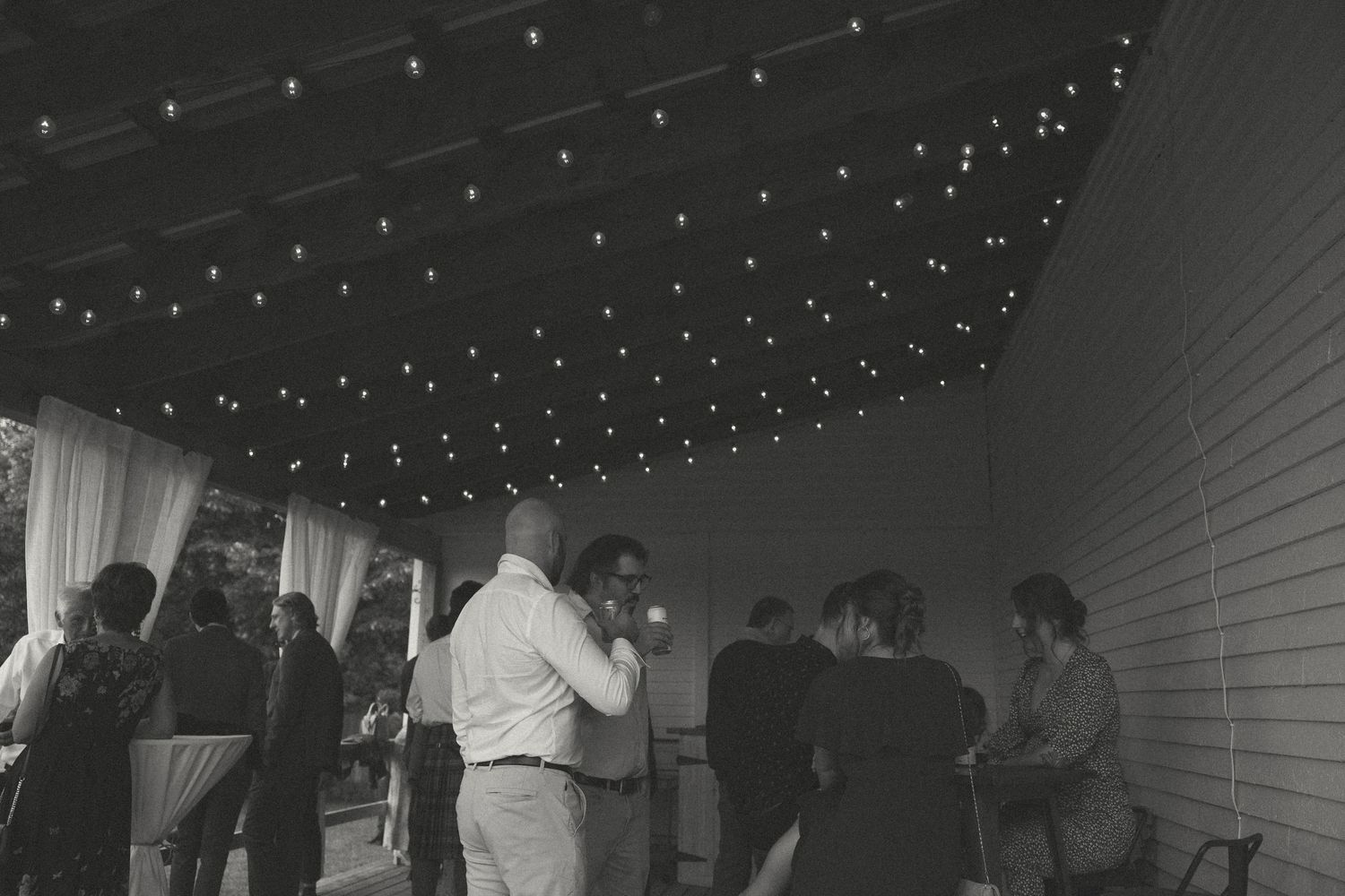 Wedding reception dance floor under string lights with guests celebrating.