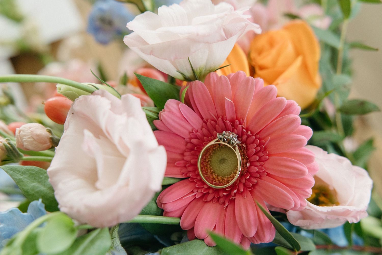 Delicate pink and coral flowers including gerbera daisies and roses with greenery.