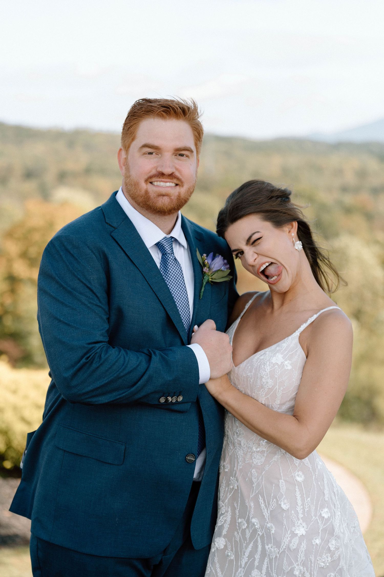 A happy couple shares joyful moments together in a scenic outdoor setting wearing formal wedding attire.