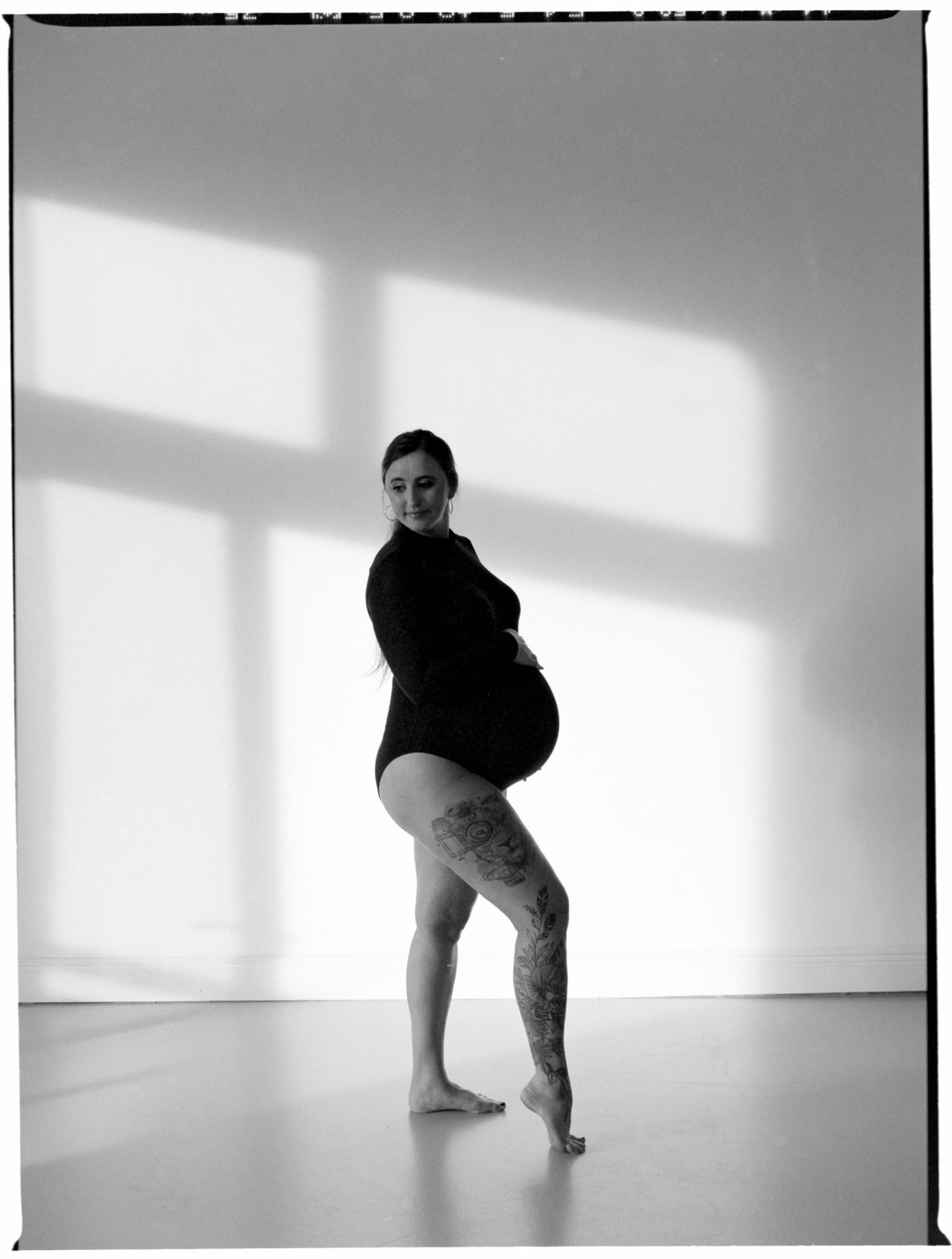 A figure in black performs a dynamic dance sequence against a white studio backdrop with dramatic shadows and lighting.