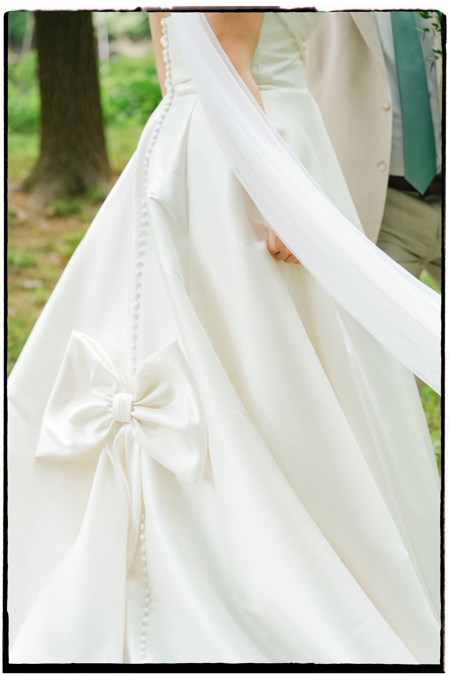 Close-up details of a white satin wedding dress with delicate pleating and fabric textures.