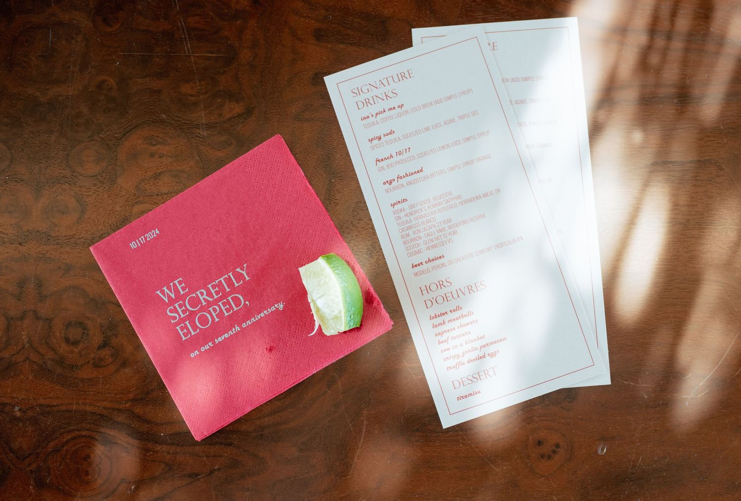 A pink tea box sits next to white paper documents on a wooden surface with natural lighting.