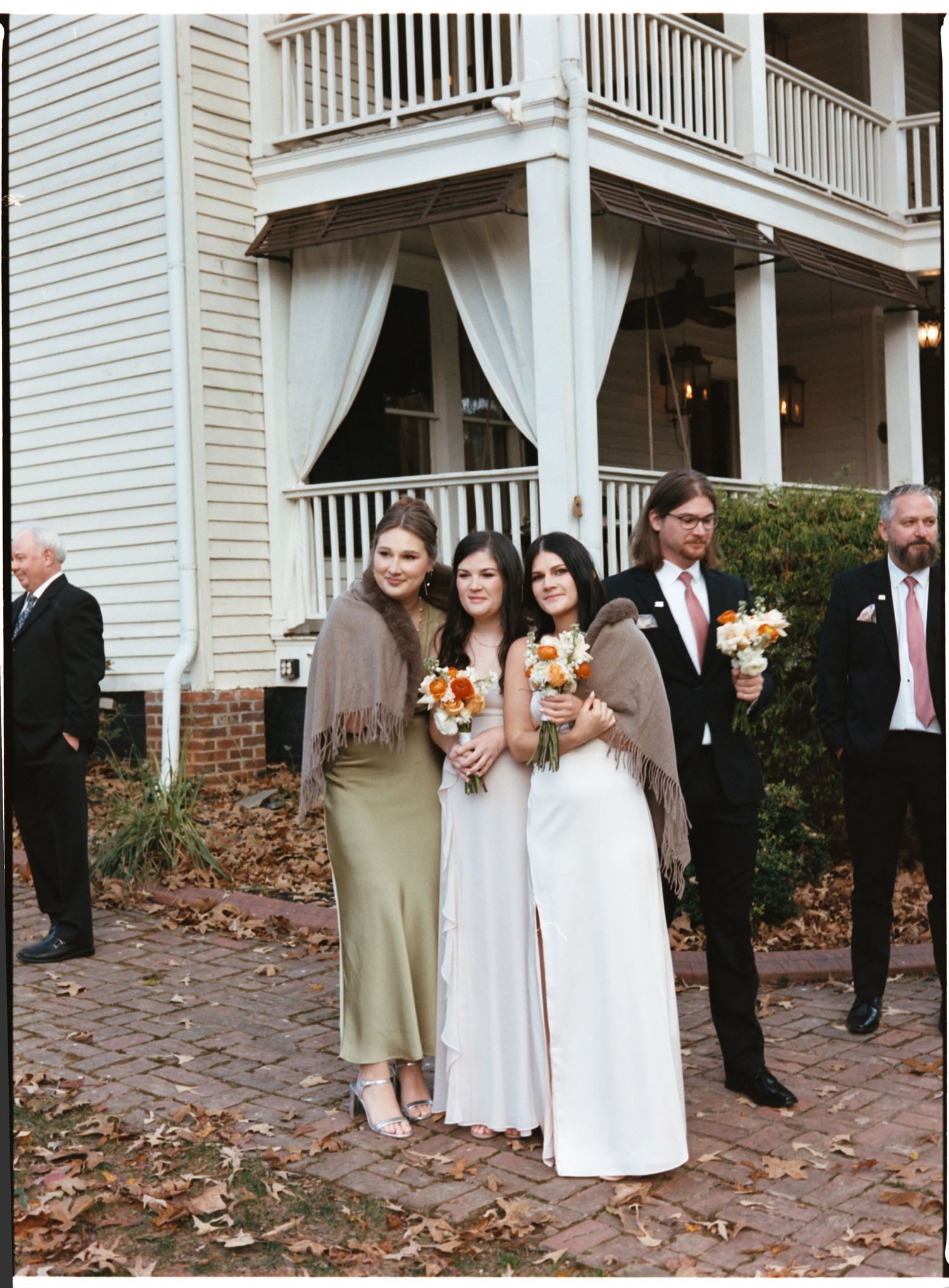A sequence of wedding party photos showing people gathered on a brick patio with white columns and curtains in the background.