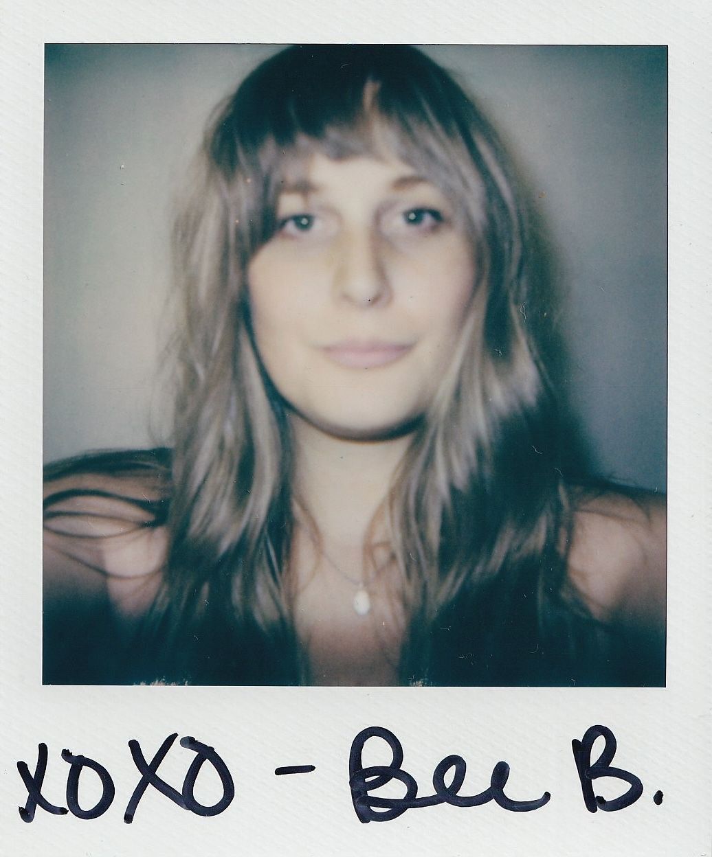 Polaroid photo of a young woman with long blonde hair and bangs, signed XOXO Bec B. in black marker.