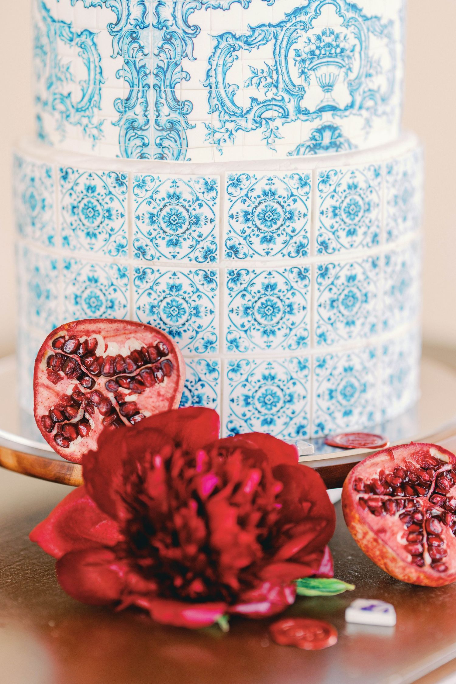 Blue and white decorative vase with ornate patterns displayed alongside cut pomegranate pieces on wooden surface.