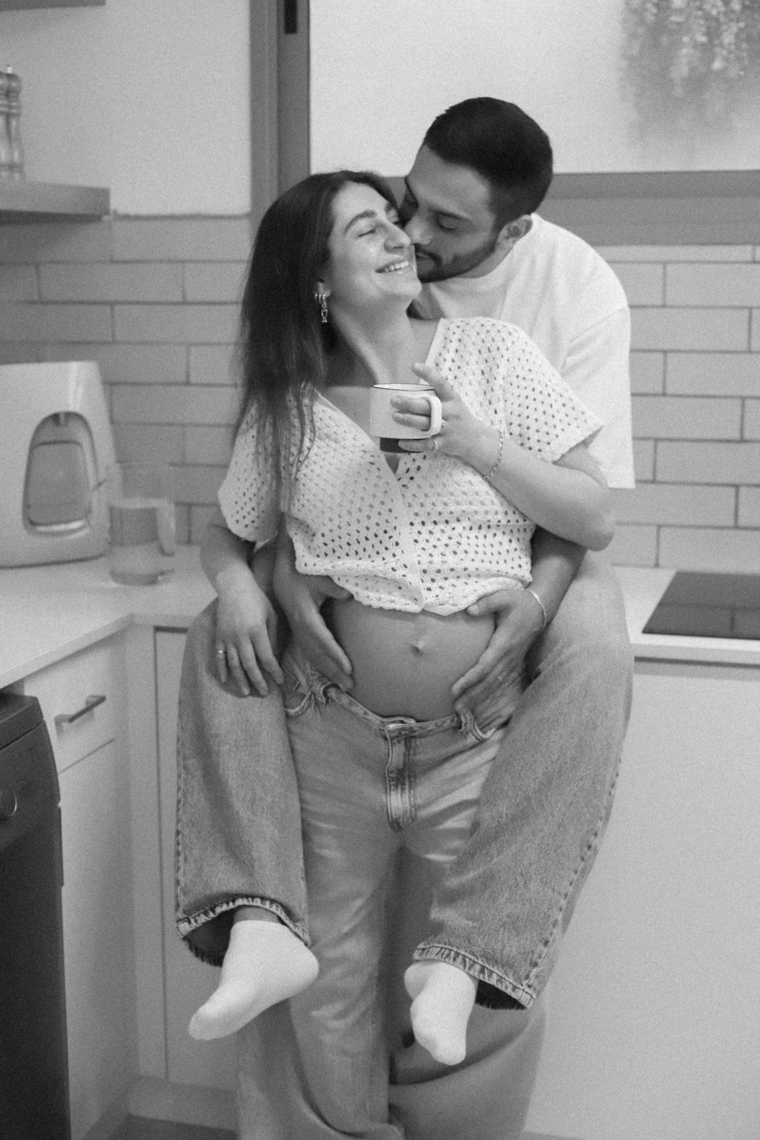 Couple sharing playful moment in kitchen in black and white photo.