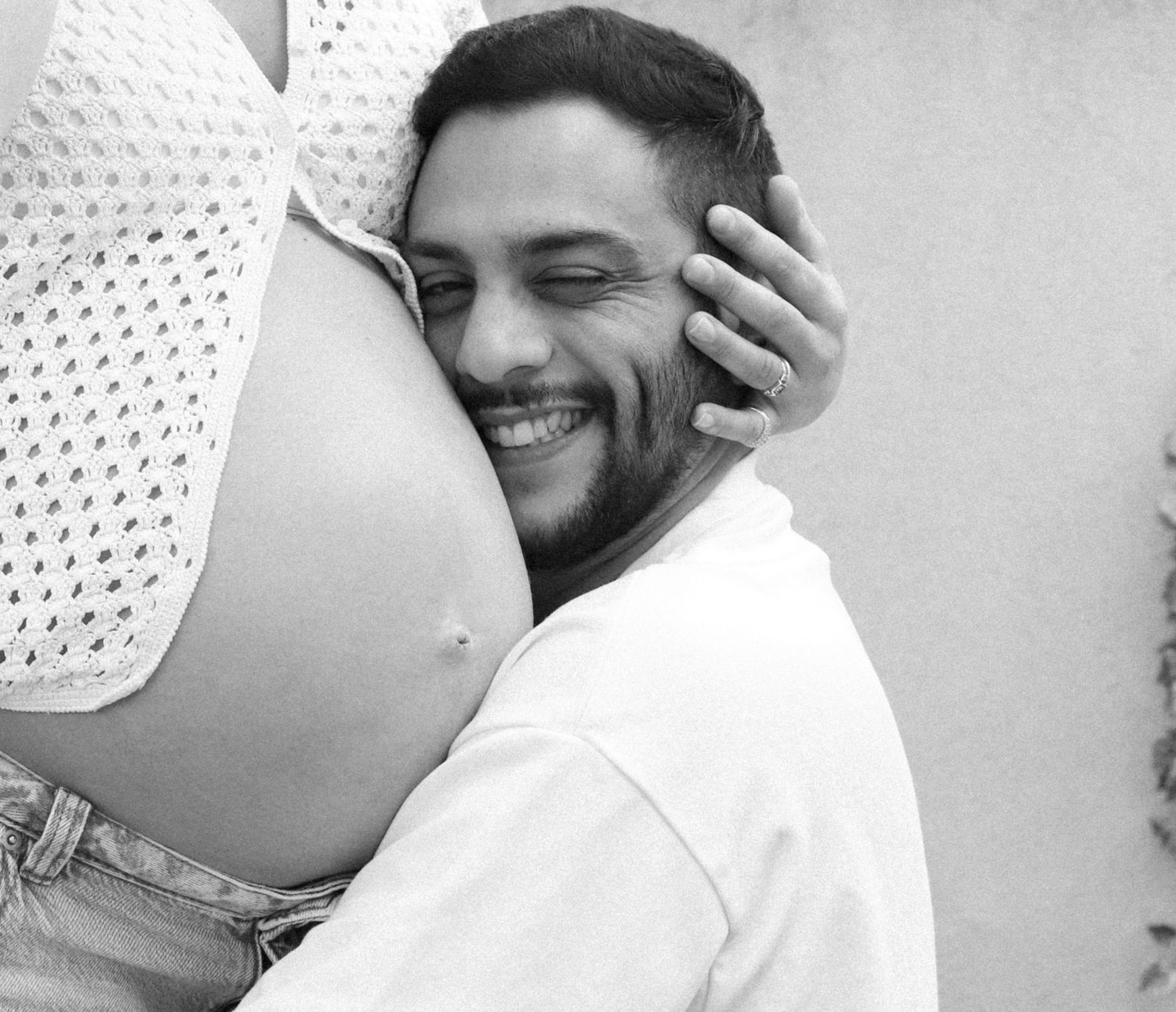 Black and white photo capturing intimate pregnancy moment outdoors.