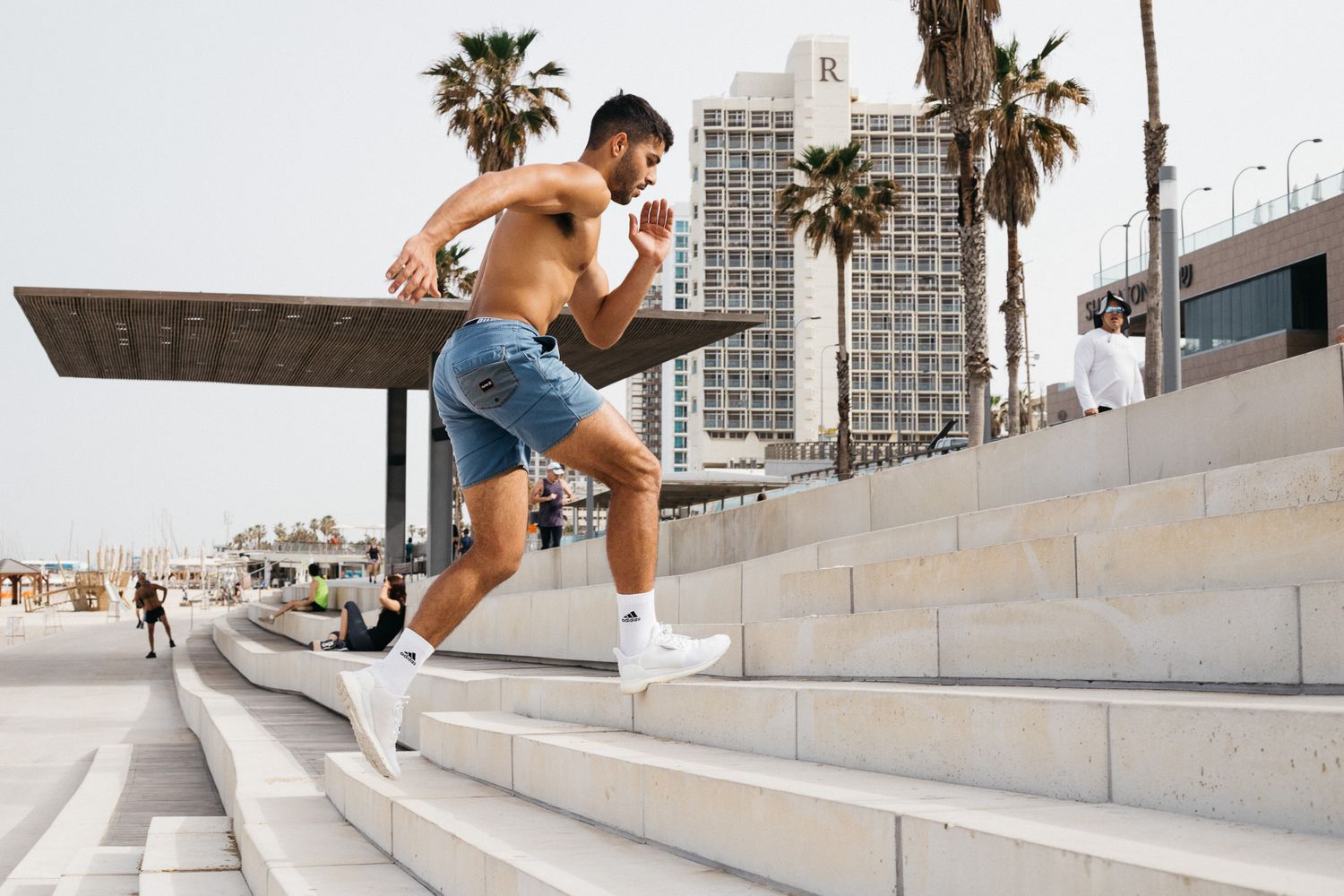 Athletic person running up concrete steps with palm trees and city buildings in background.