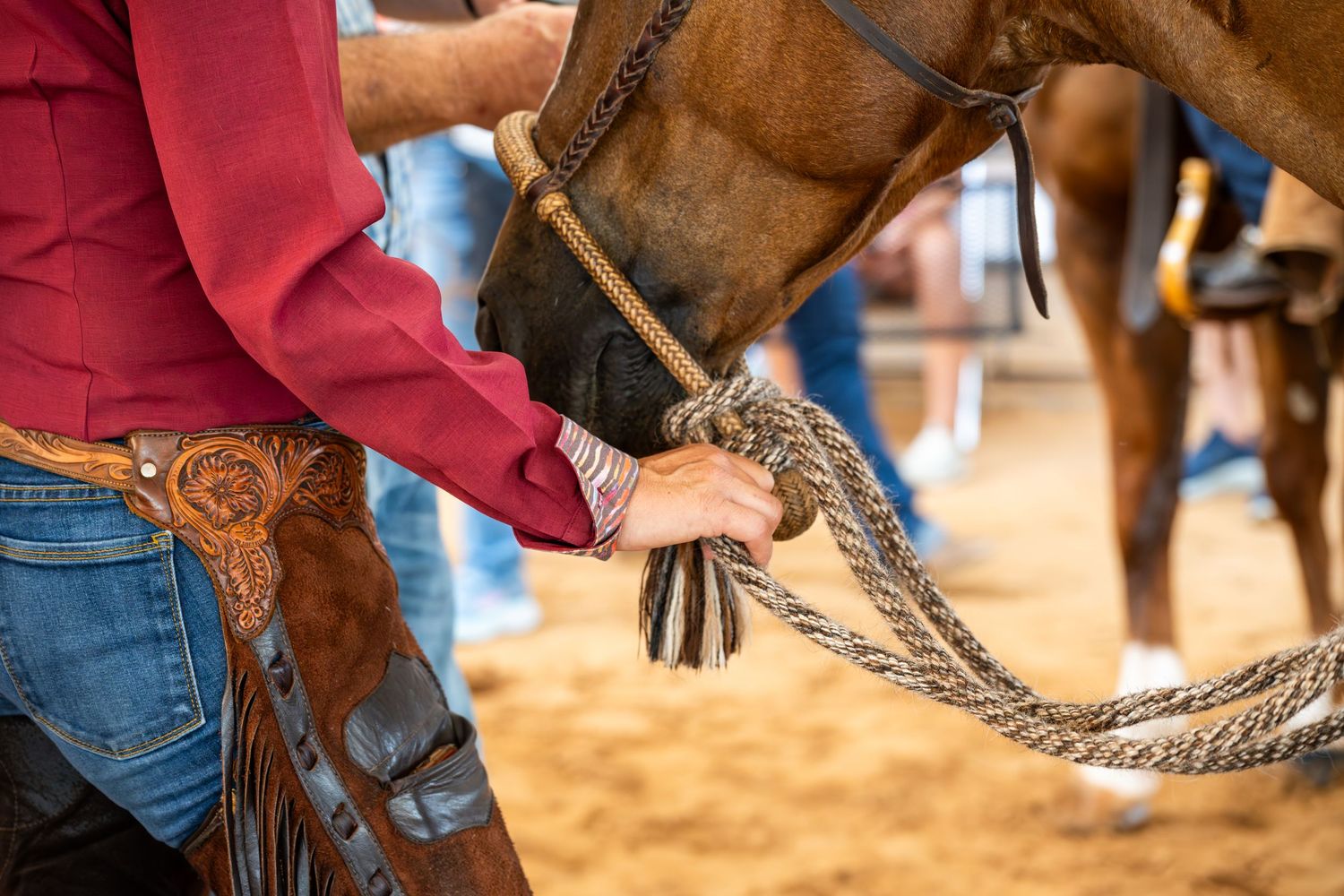 Close-up of horse's bridle and reins being handled during rodeo competition.