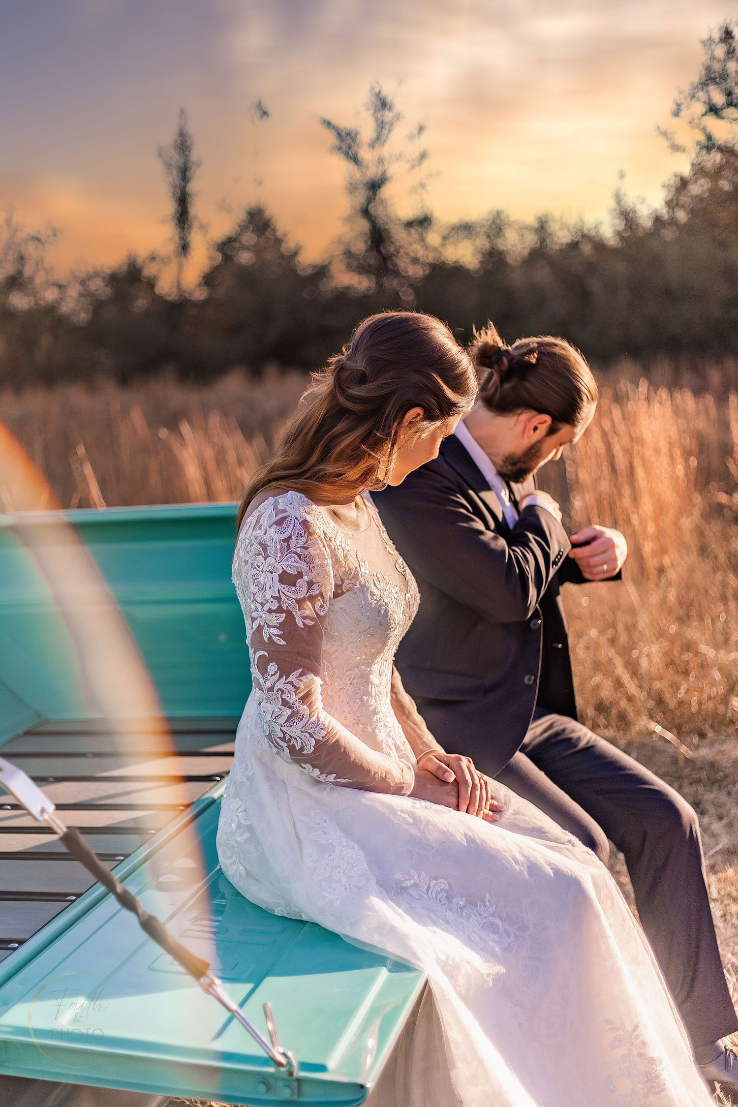 Bride and groom sit intimately on a turquoise truck at sunset, surrounded by golden fields.