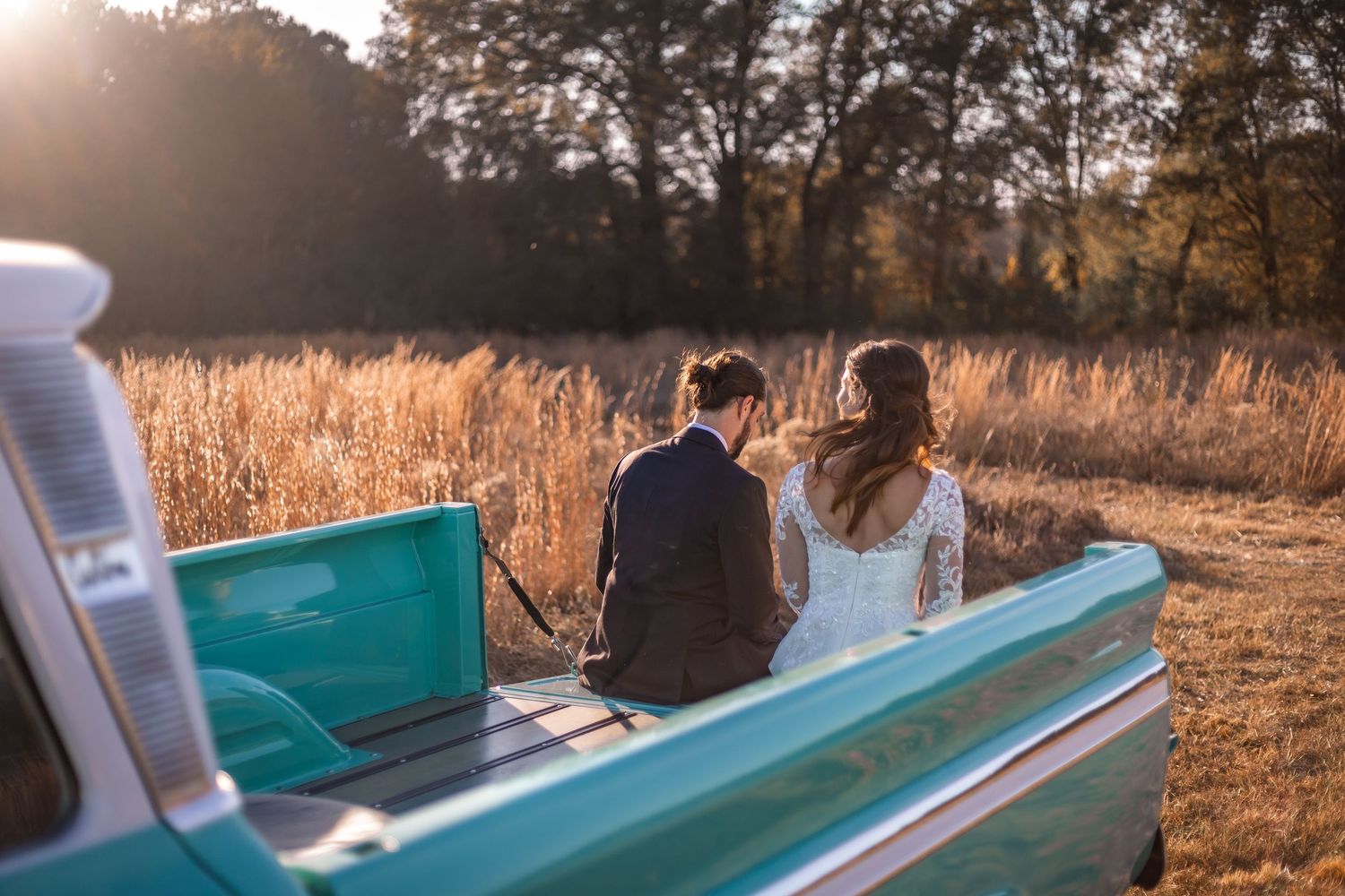 A teal vintage convertible car parked in a golden autumn field during sunset with warm lighting.