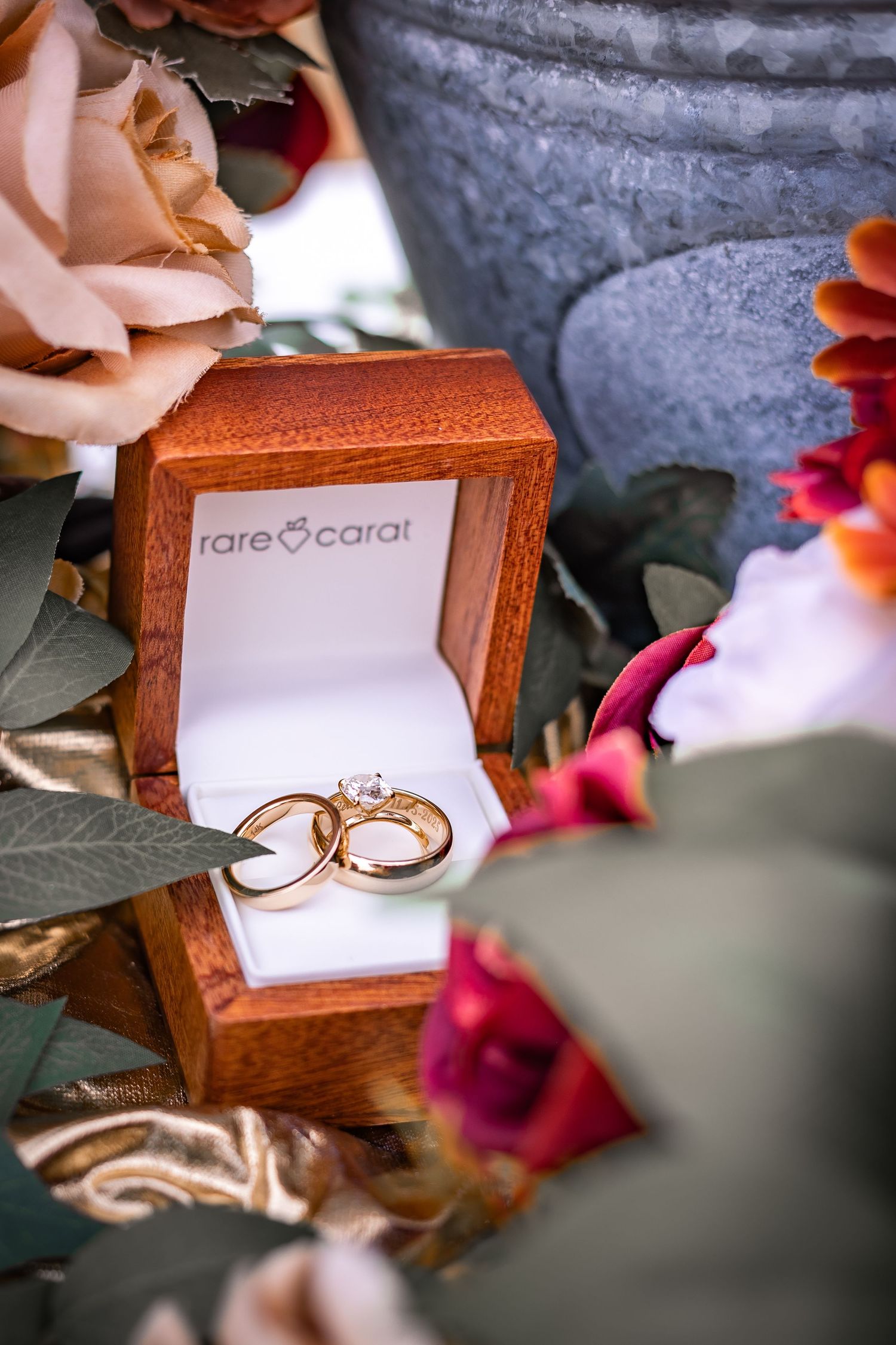 Rose gold engagement ring displayed in a wooden jewelry box with red roses in the background.