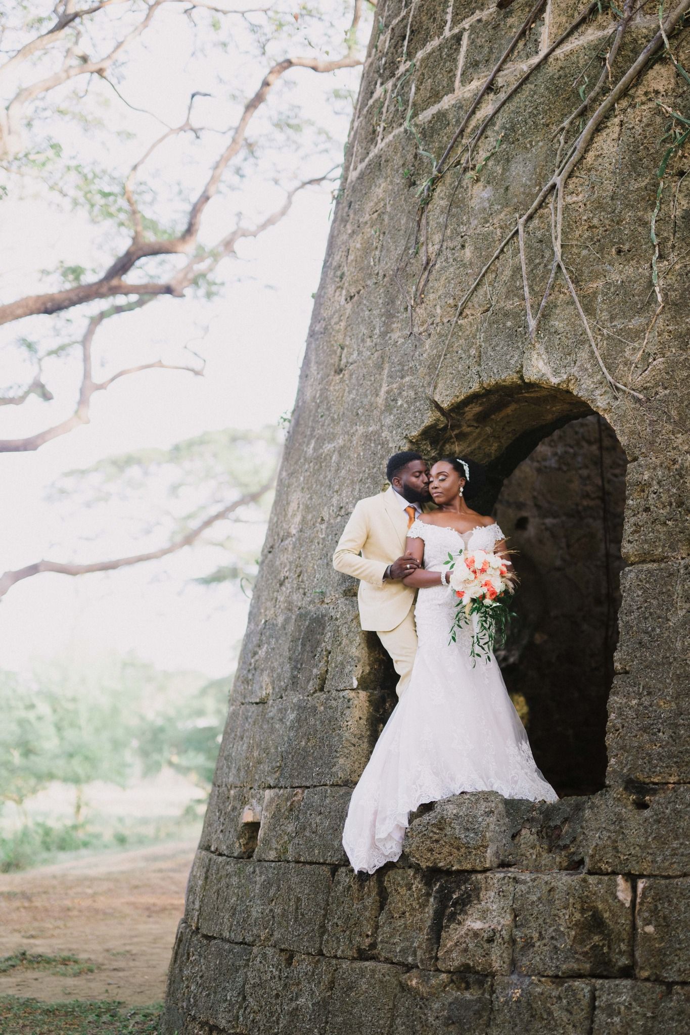Newlyweds pose together in stone archway during romantic outdoor wedding photo session.