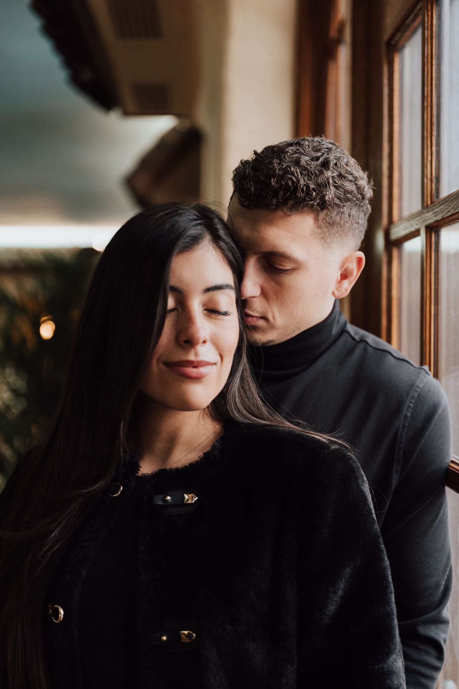 engaged couple with eyes closed and smiling posing for photoshoot