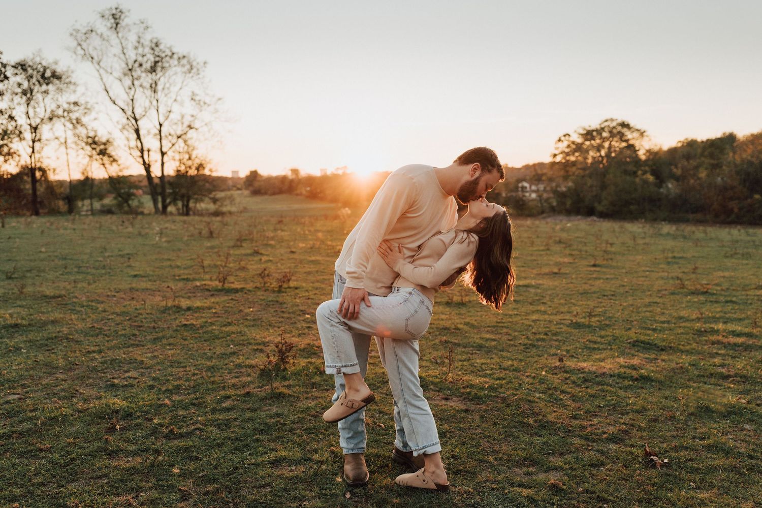 A couple embraces in a golden field at sunset during a romantic outdoor engagement photoshoot in Middletown, PA
