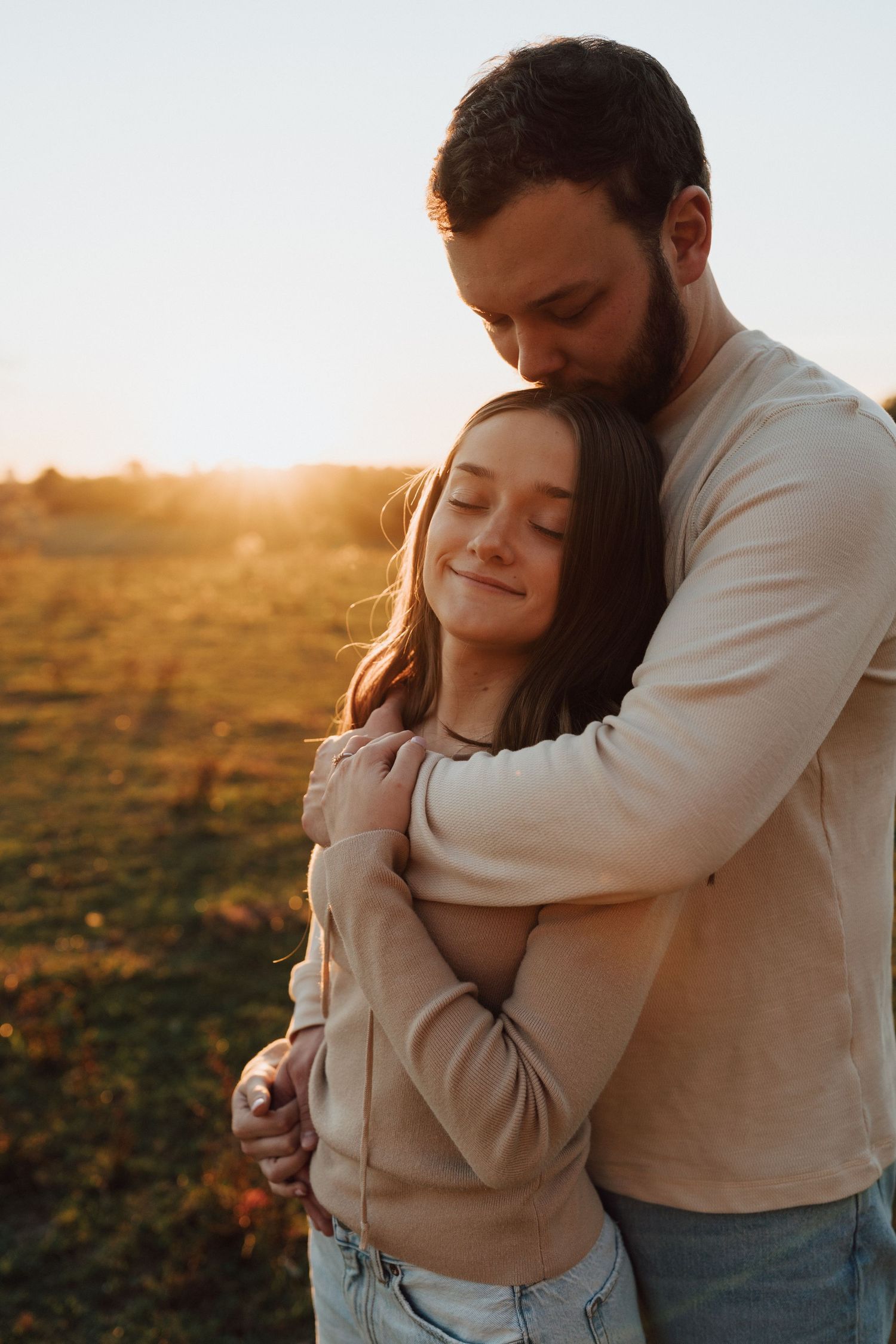 A couple embraces tenderly in a golden sunset field during a romantic fall season outdoor engagement photoshoot in Middletown, PA