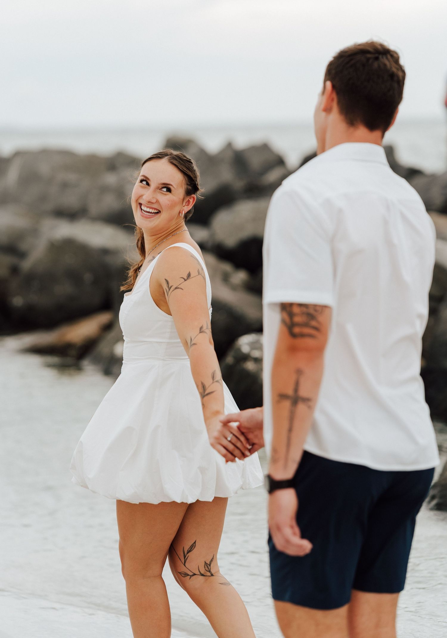 Engaged Couple in casual white outfits holding hands and smiling at St. Petersburg, Florida for engagement photoshoot.