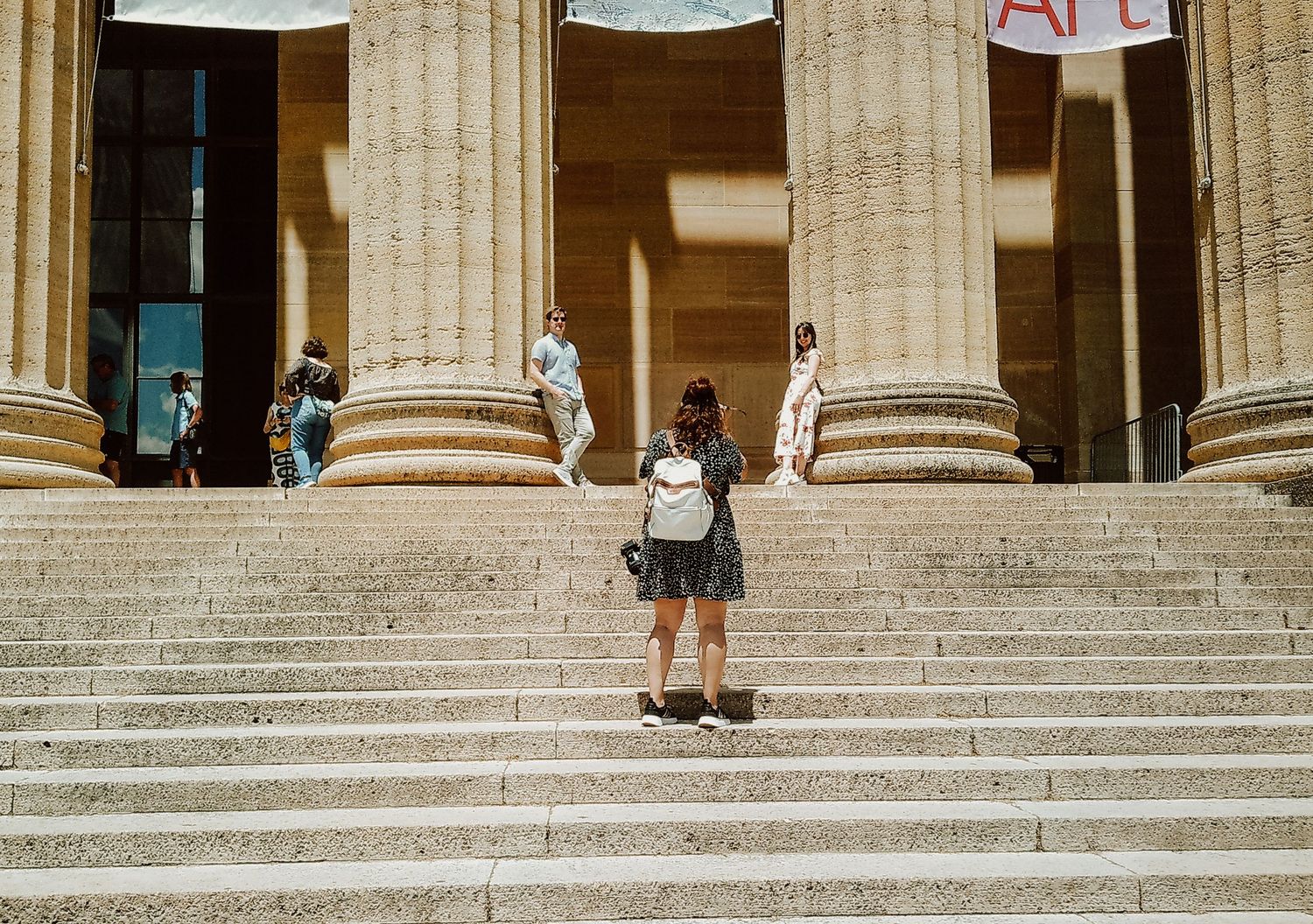 Student standing on grand stone steps of historic building with classical columns.