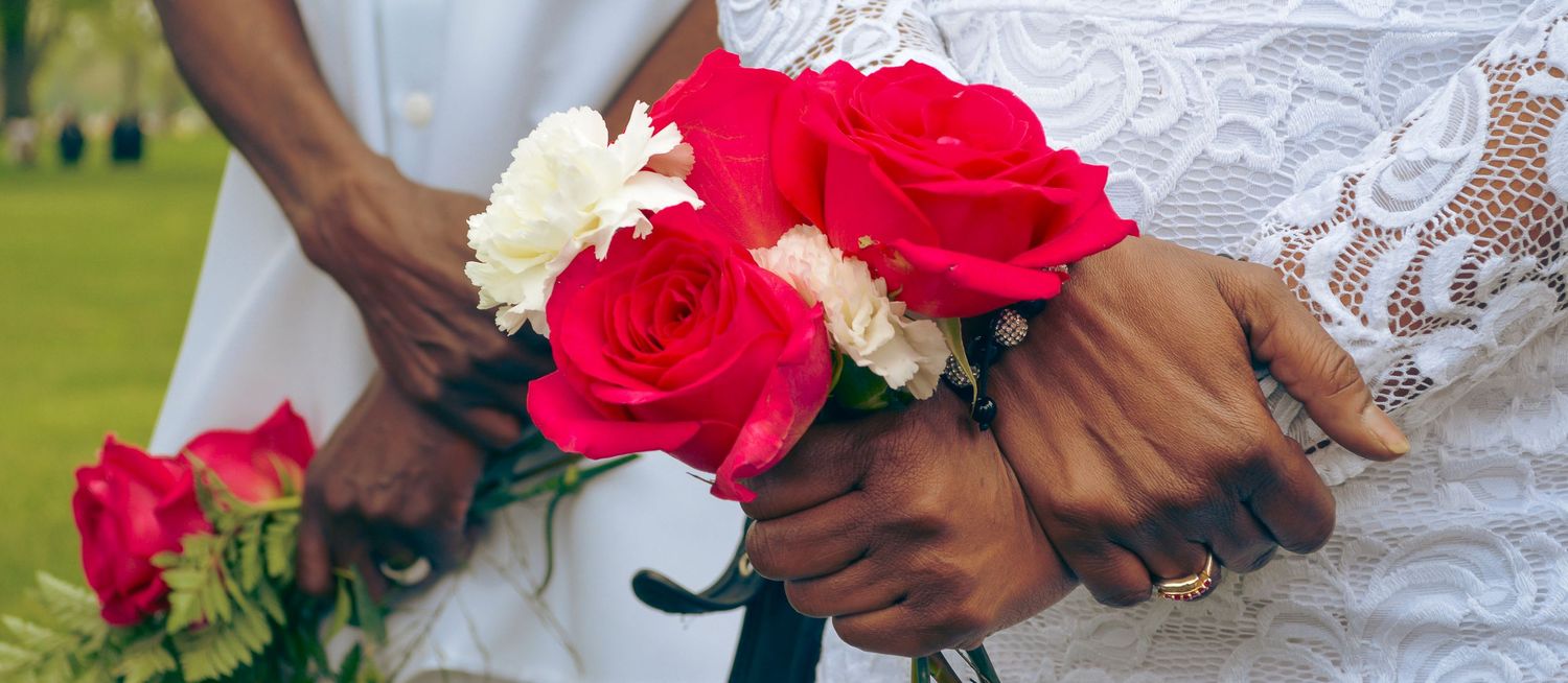 Photo of a couple holding red and white roses.