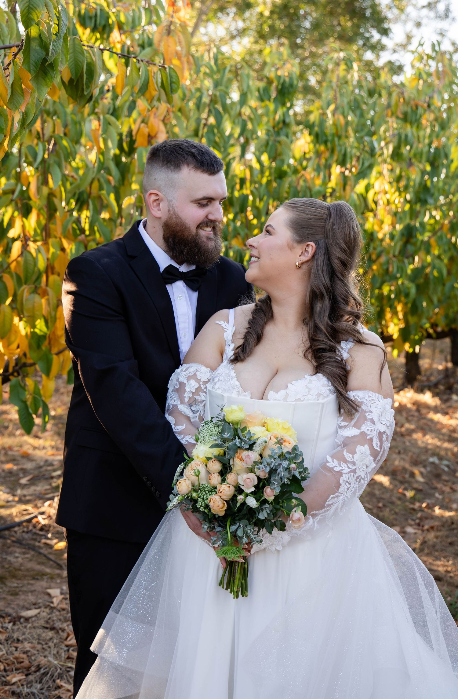 A romantic wedding couple shares tender moments among yellow autumn foliage in a picturesque outdoor setting.