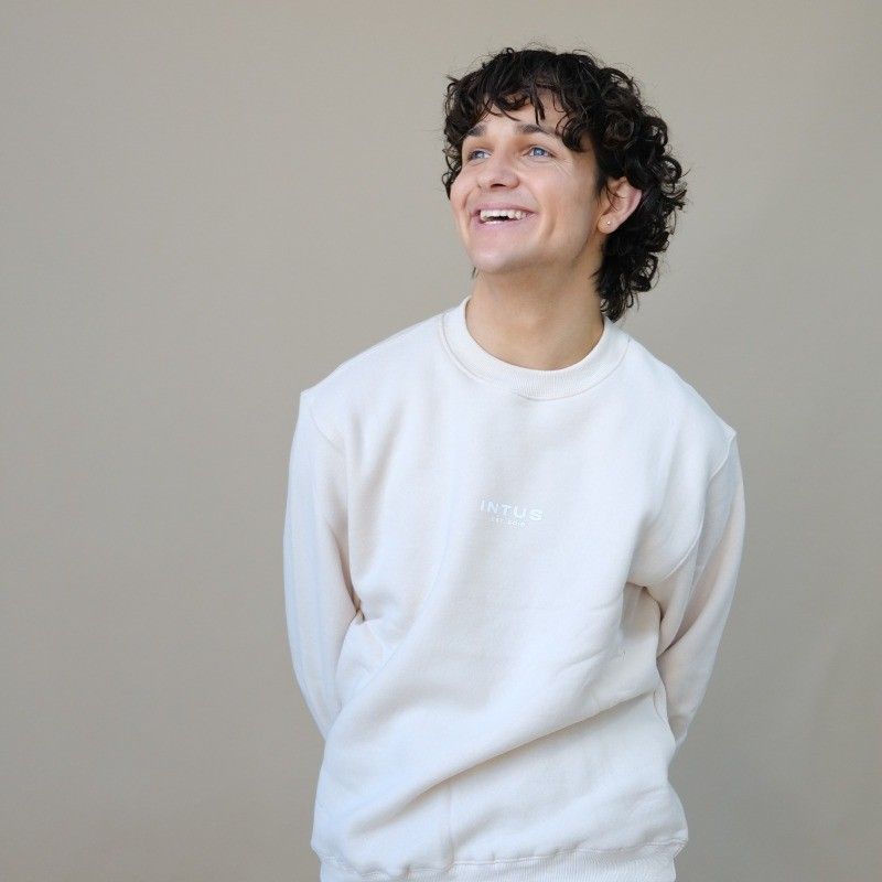 Person in white sweatshirt laughing and posing against neutral background in candid photo series.