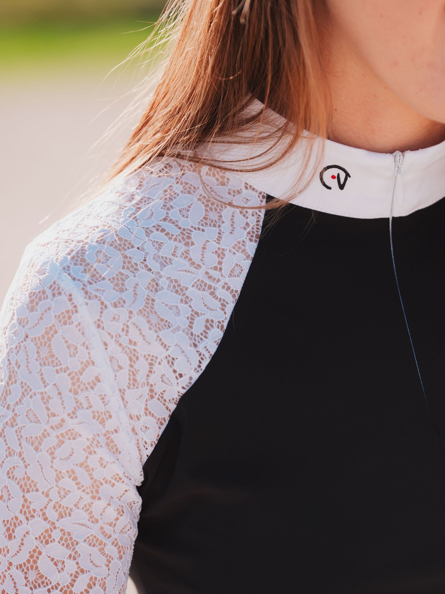 Athletic top with black body and delicate white lace raglan sleeves featuring a small logo at the collar.