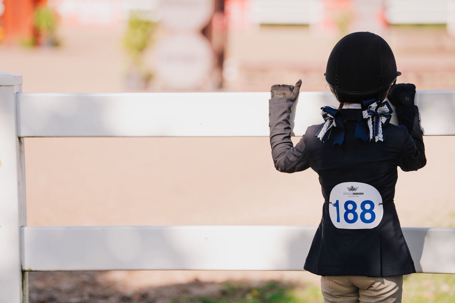 A row of marathon runners with numbered bibs participate in a race on a paved path.