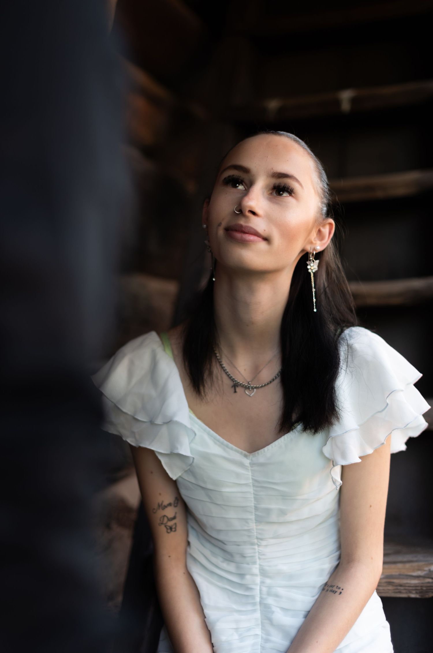 Portrait of woman in white ruffled dress against rustic wooden background.