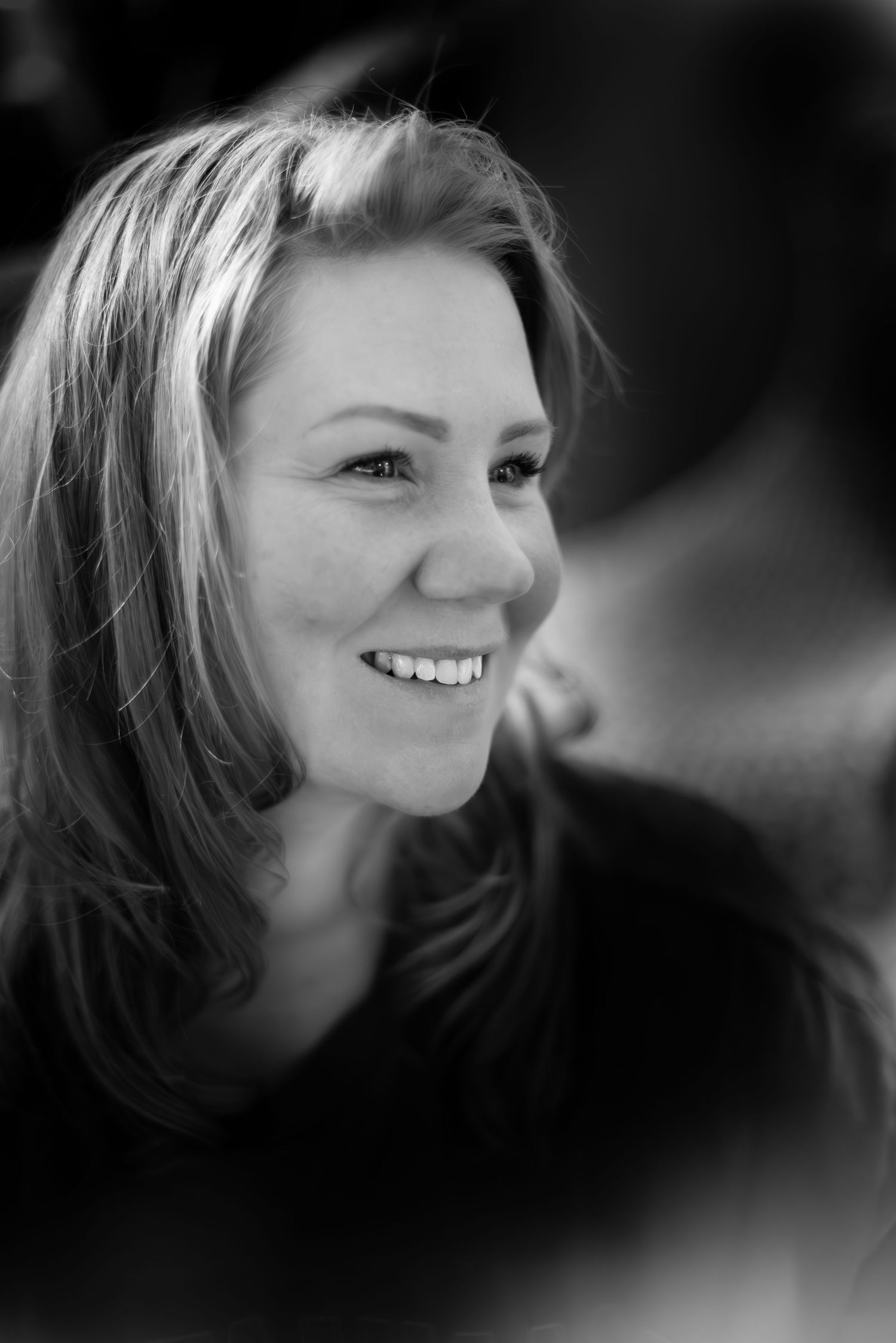A black and white portrait showing a joyful expression and candid smile in natural lighting.