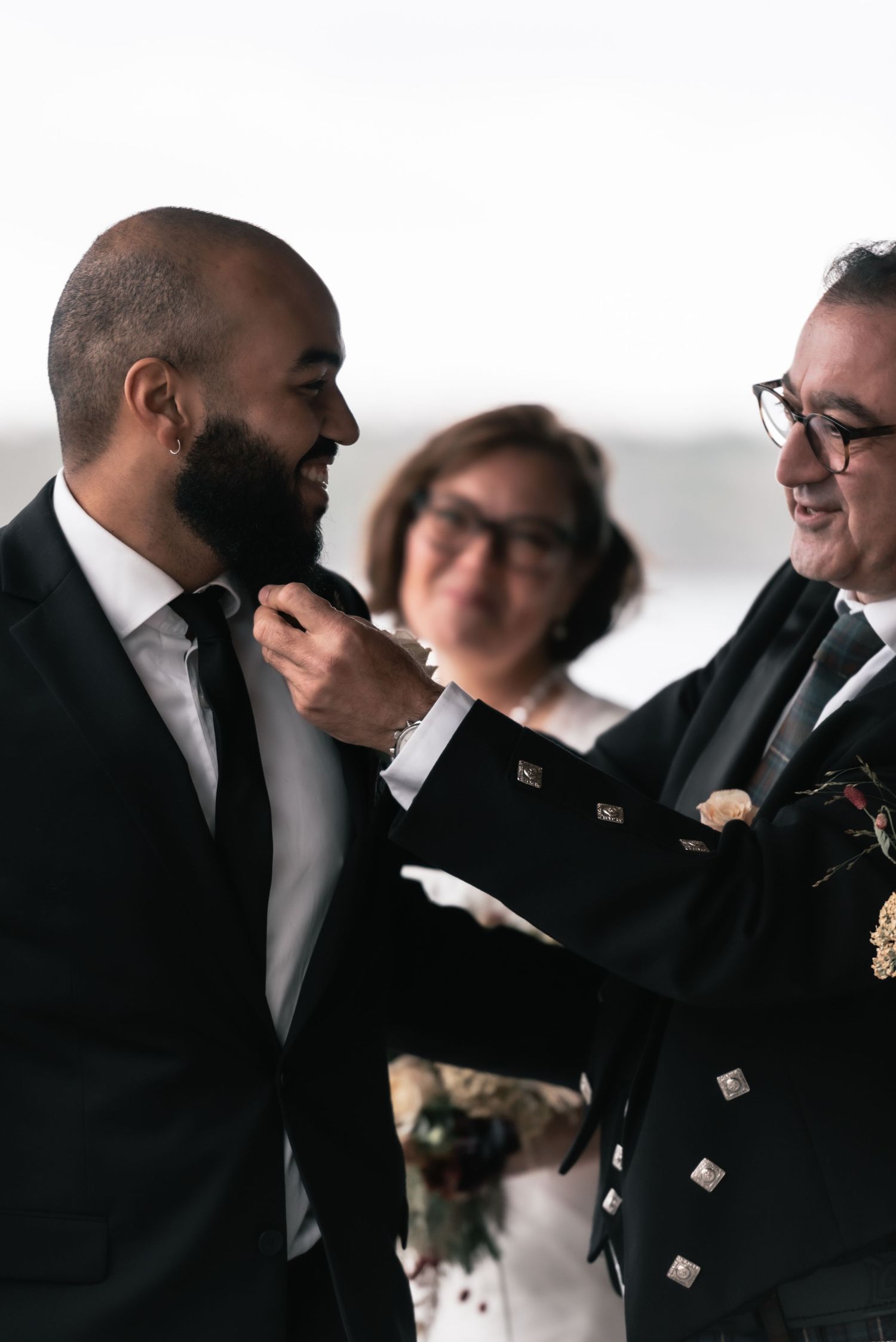 Two people share a joyful moment during a Scottish wedding ceremony with a kilted officiant.